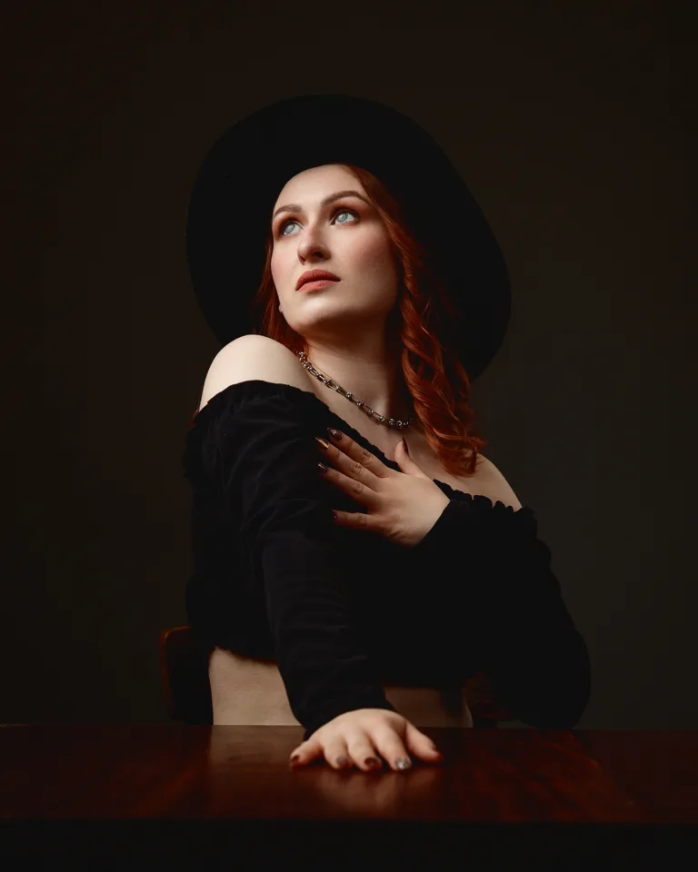 Red-haired woman in black hat, dramatic portrait