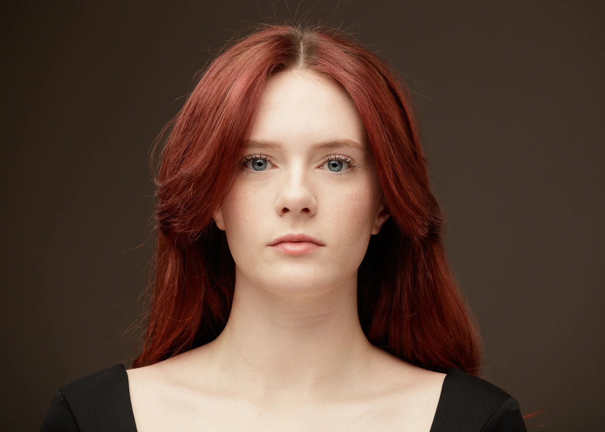Studio portrait of red-haired woman against brown background