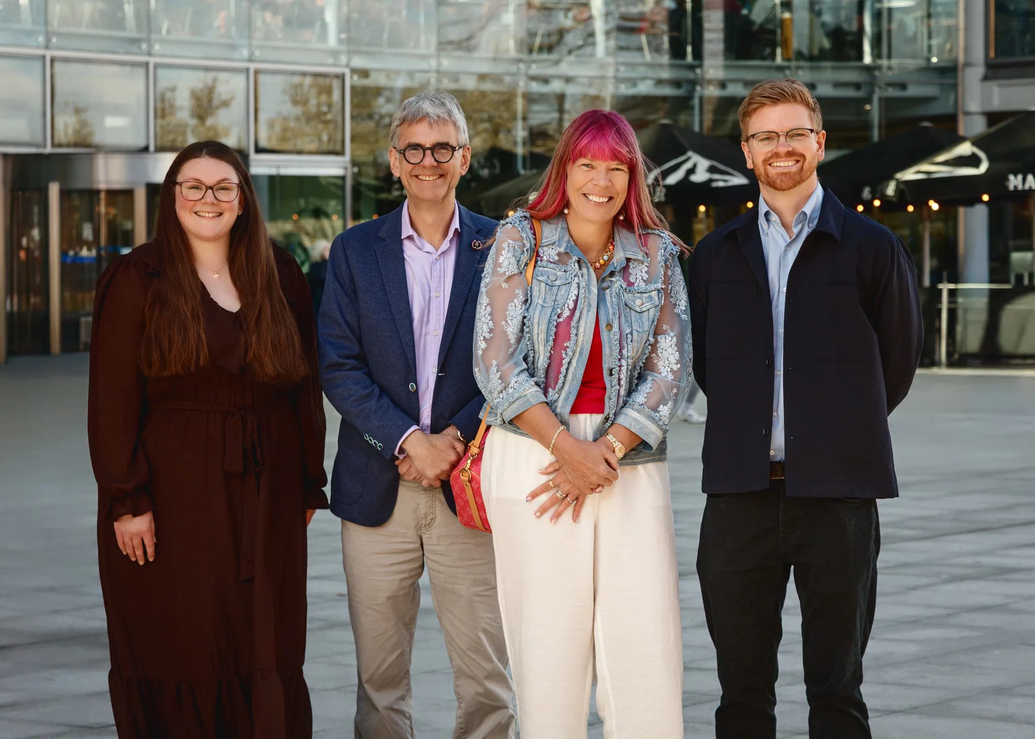 Four adults smiling outside modern office building