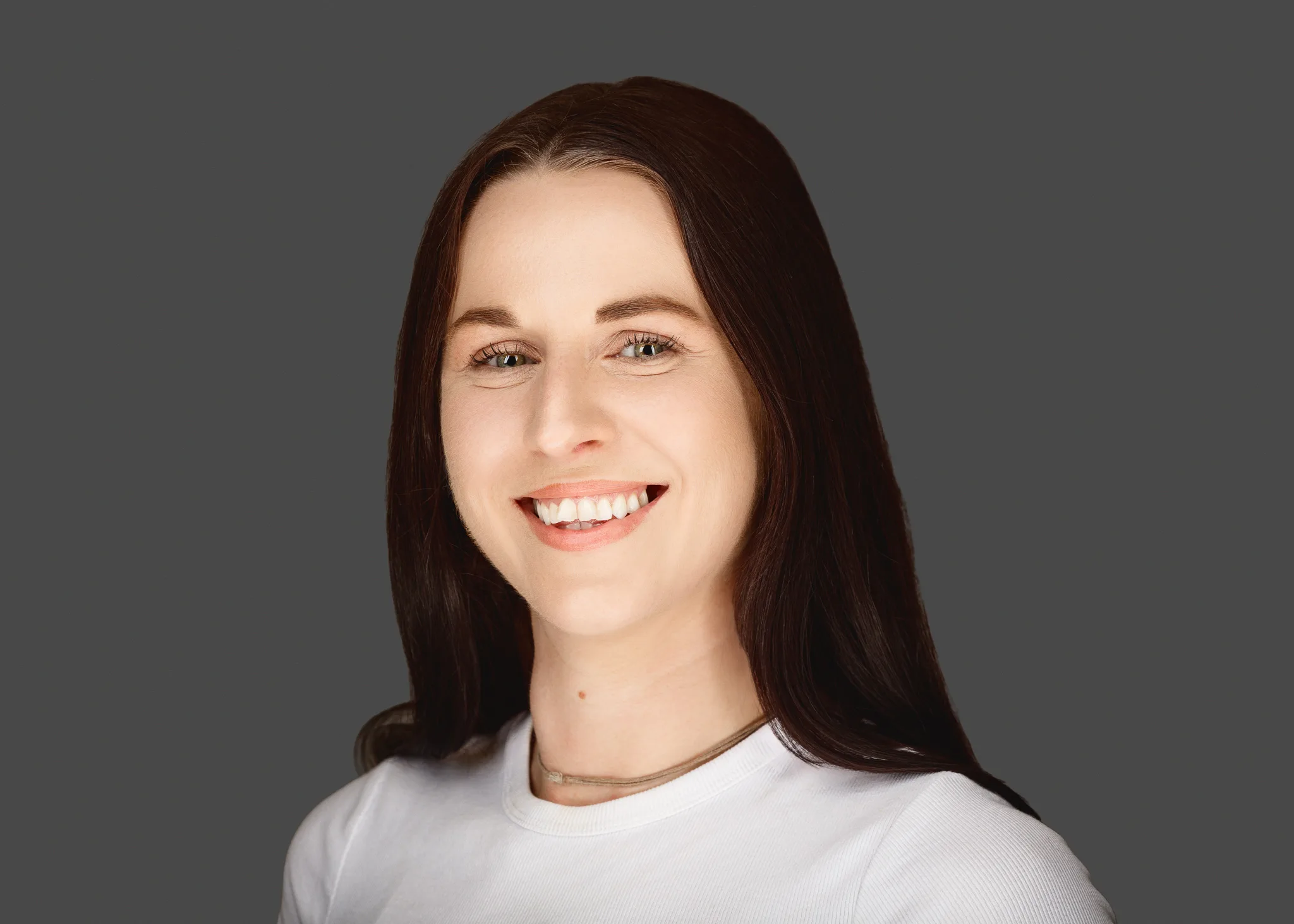 Smiling woman with long dark hair, grey background
