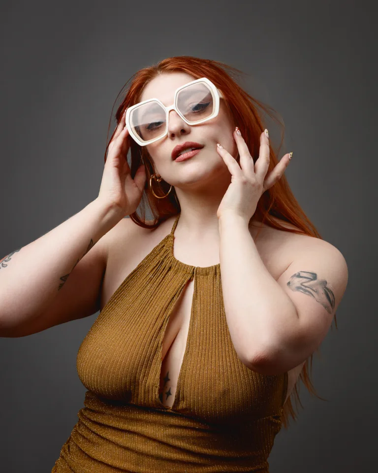 Red-haired woman in white sunglasses and gold dress