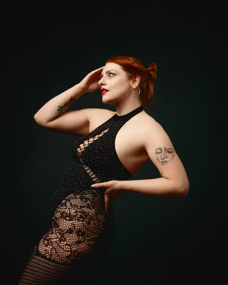 Red-haired woman posing in black lace dress