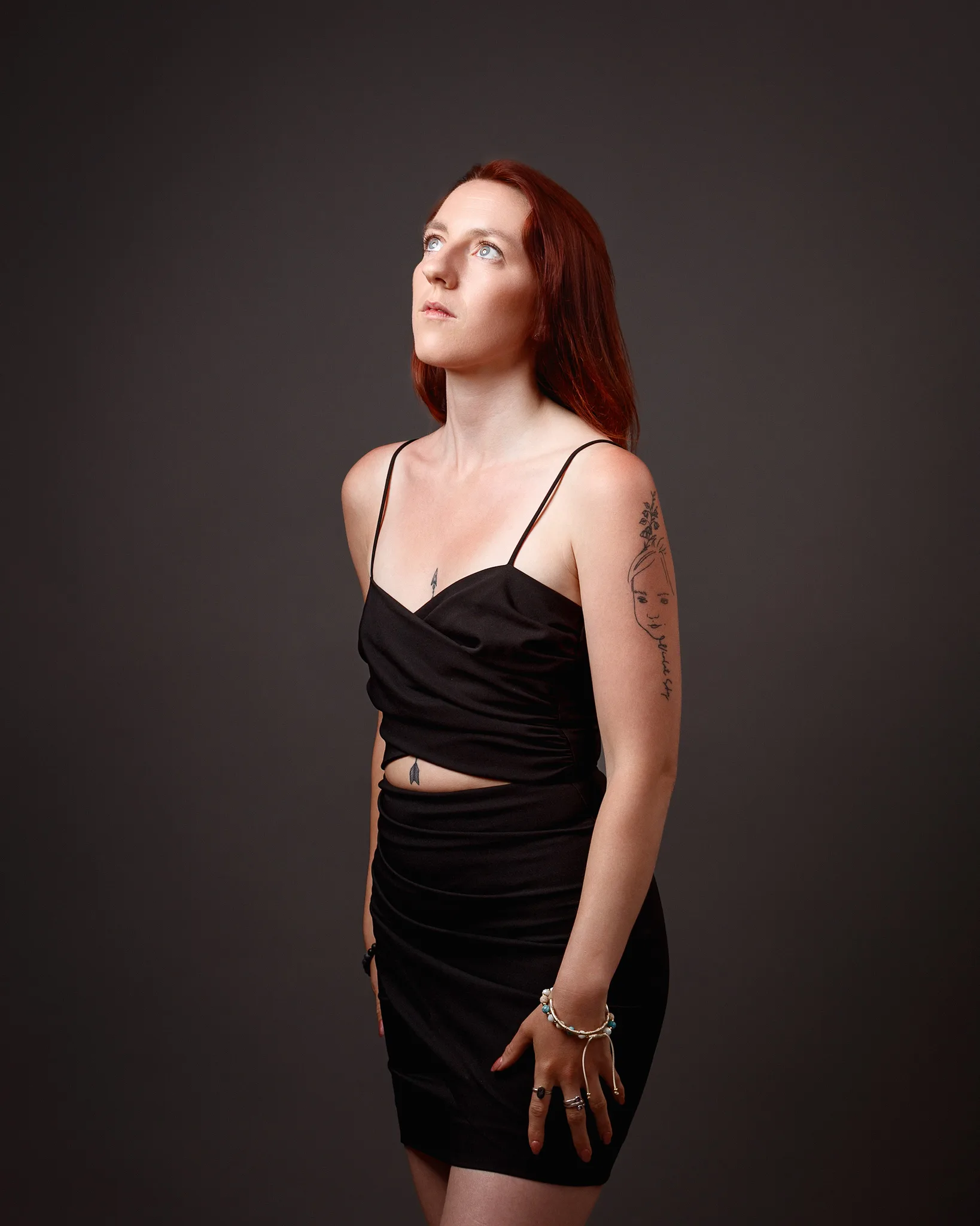 Red-haired woman in black dress looking upward