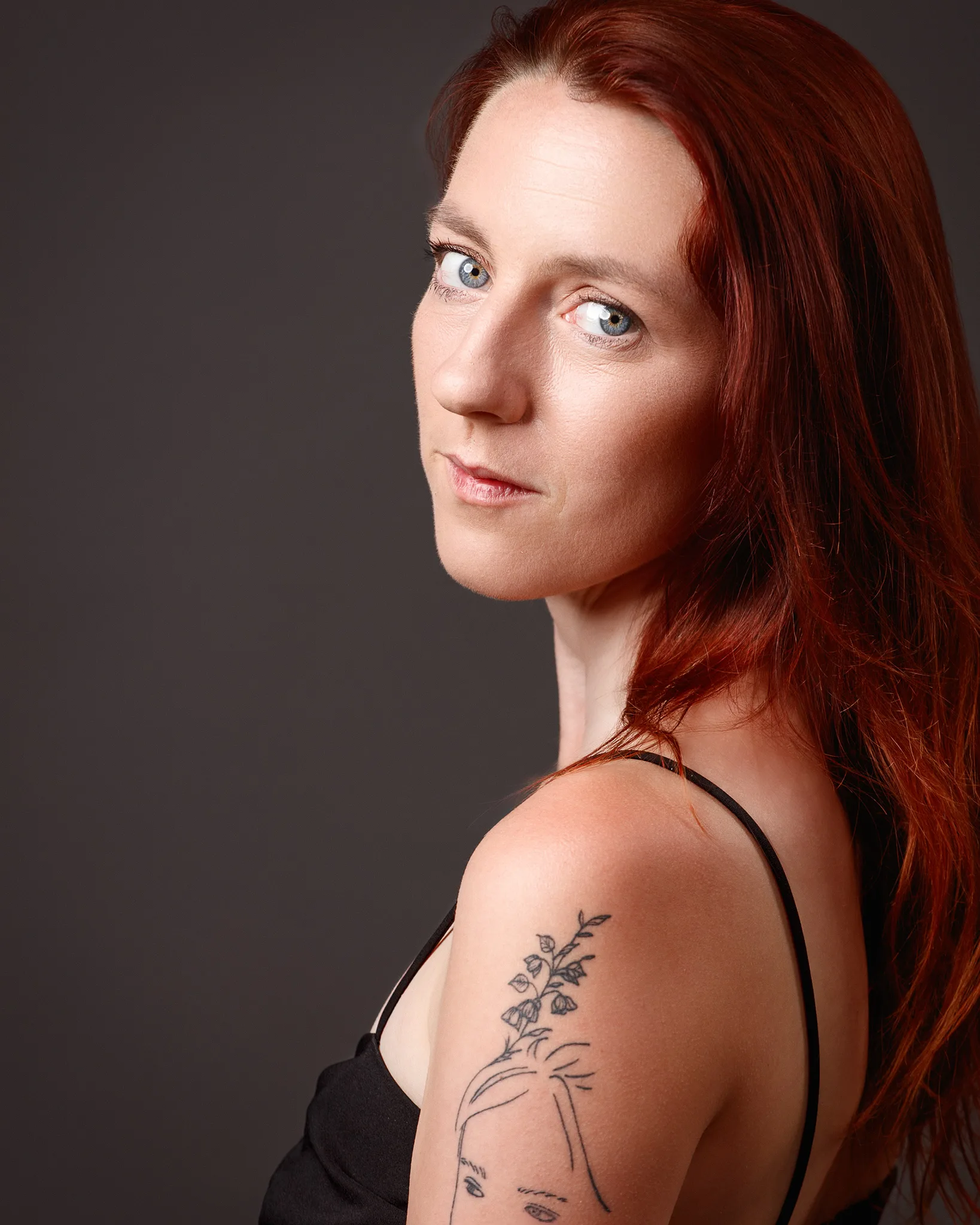 Red-haired woman with floral arm tattoo portrait