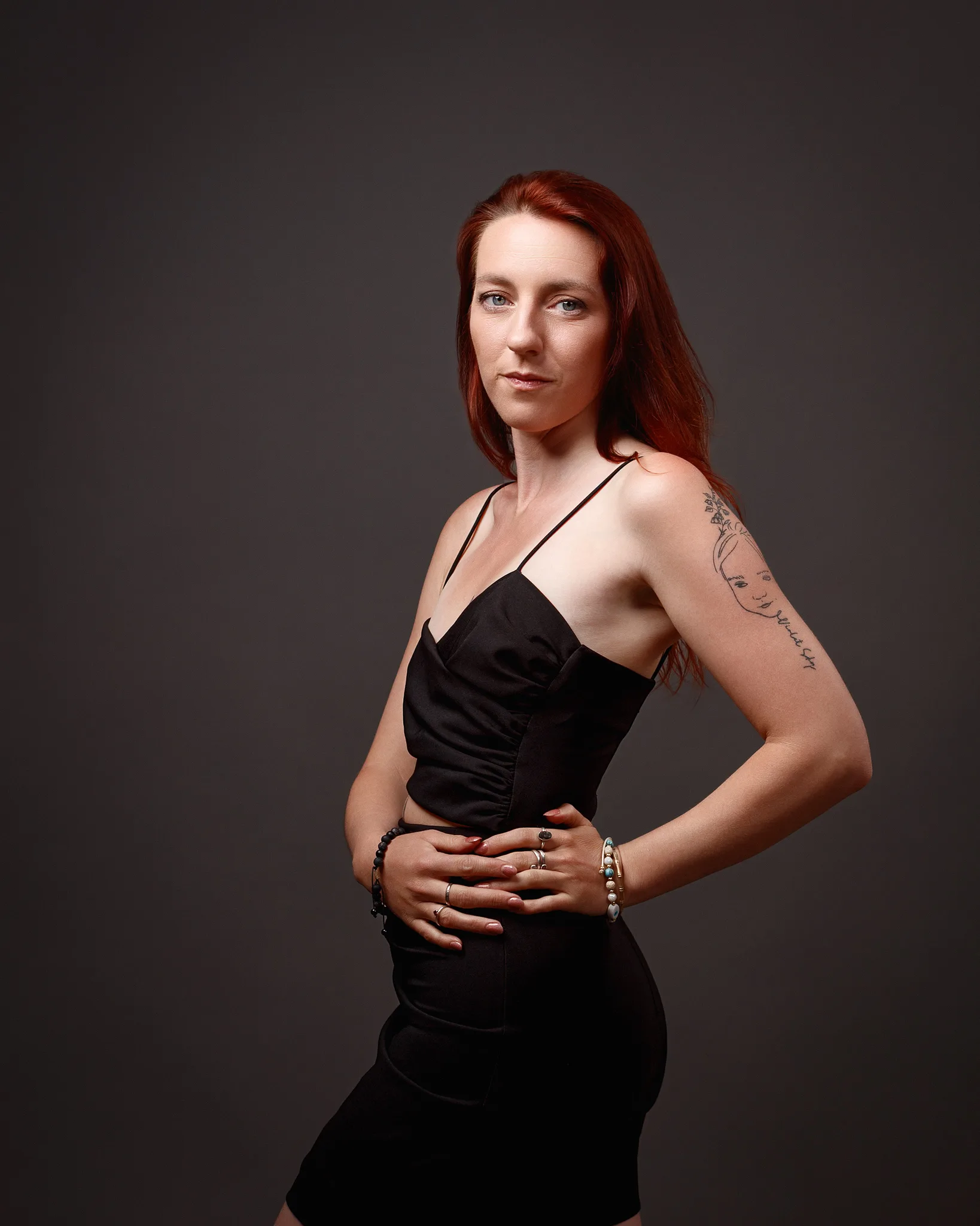 Red-haired woman in black dress with arm tattoo