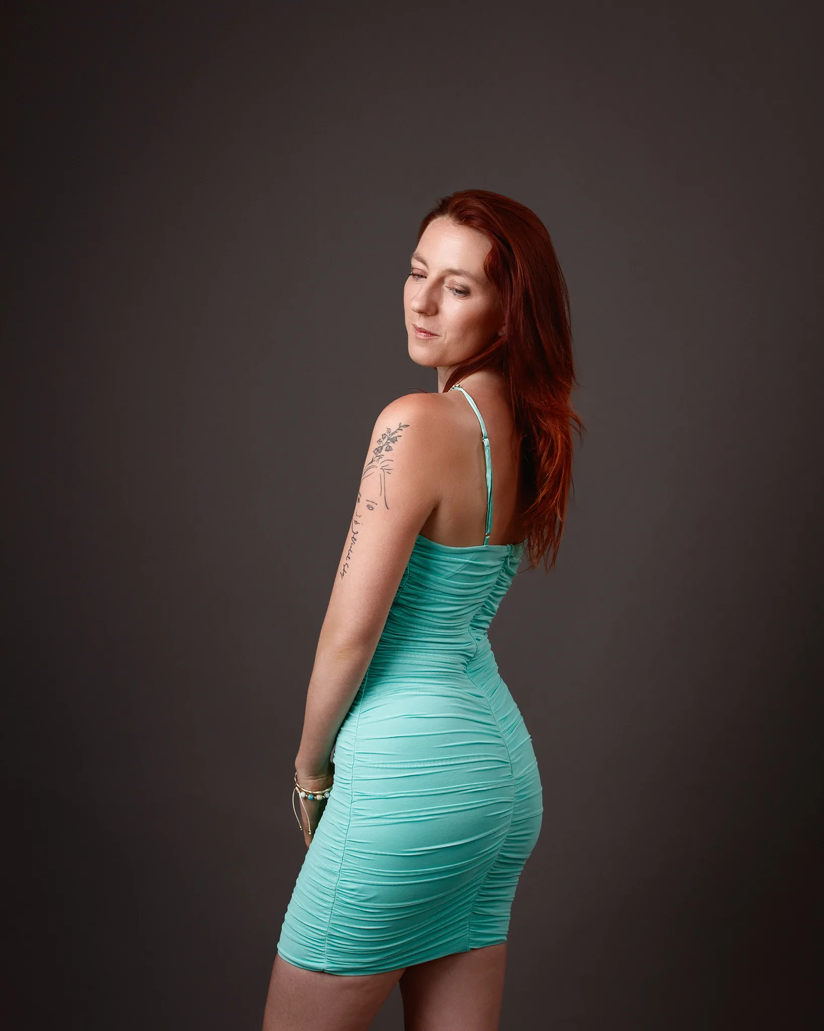 Woman in turquoise dress looking over shoulder