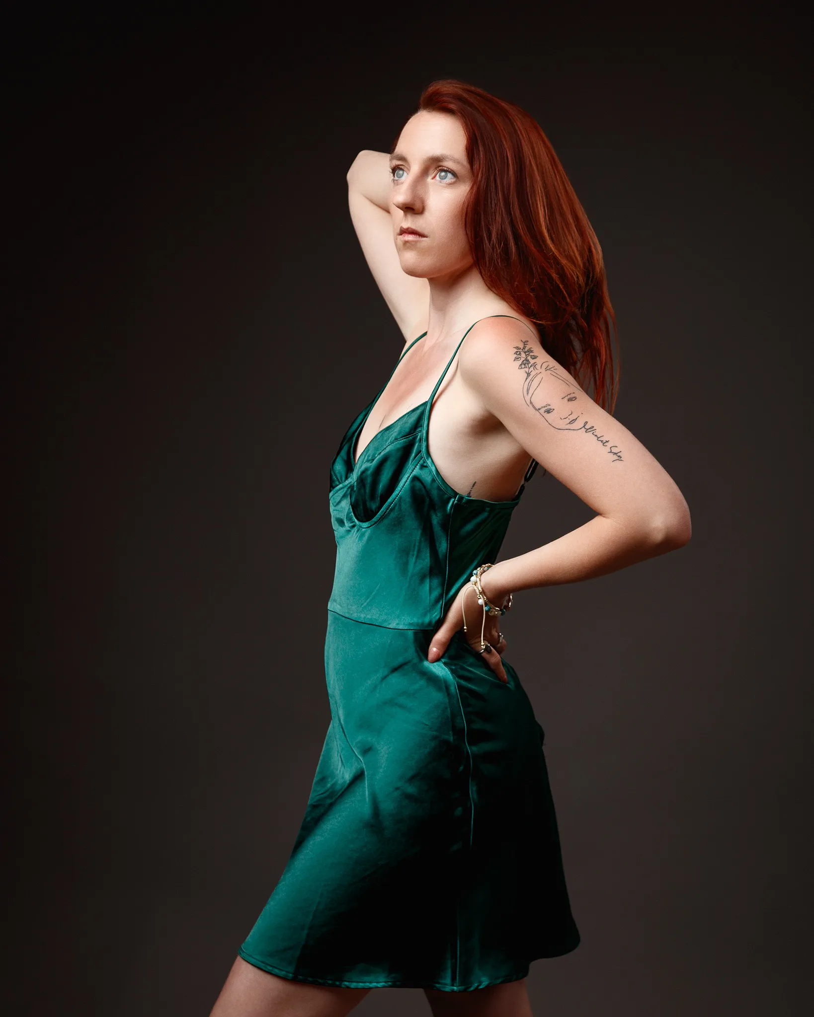 Red-haired woman in green satin dress posing
