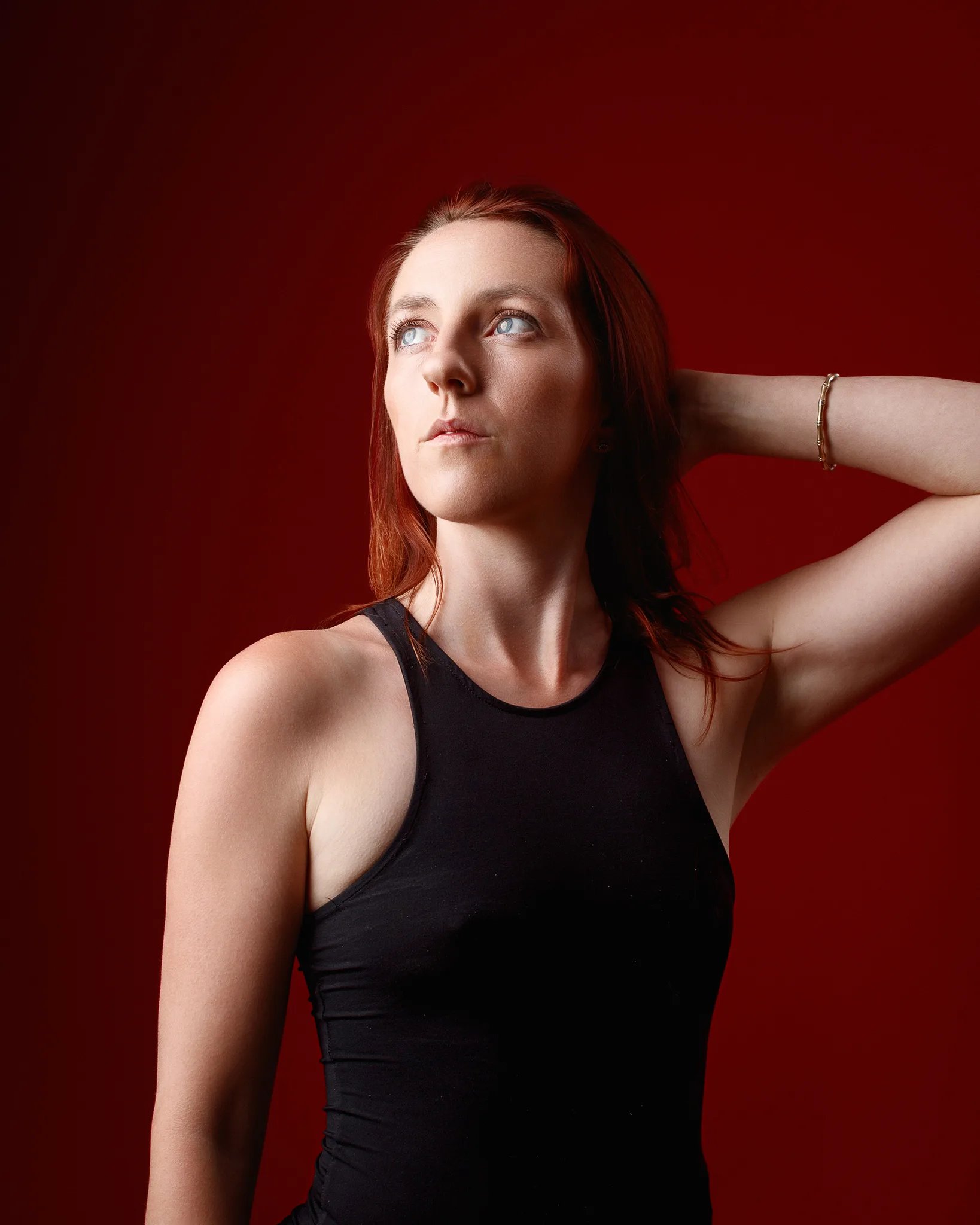 Red-haired woman posing against bold red background