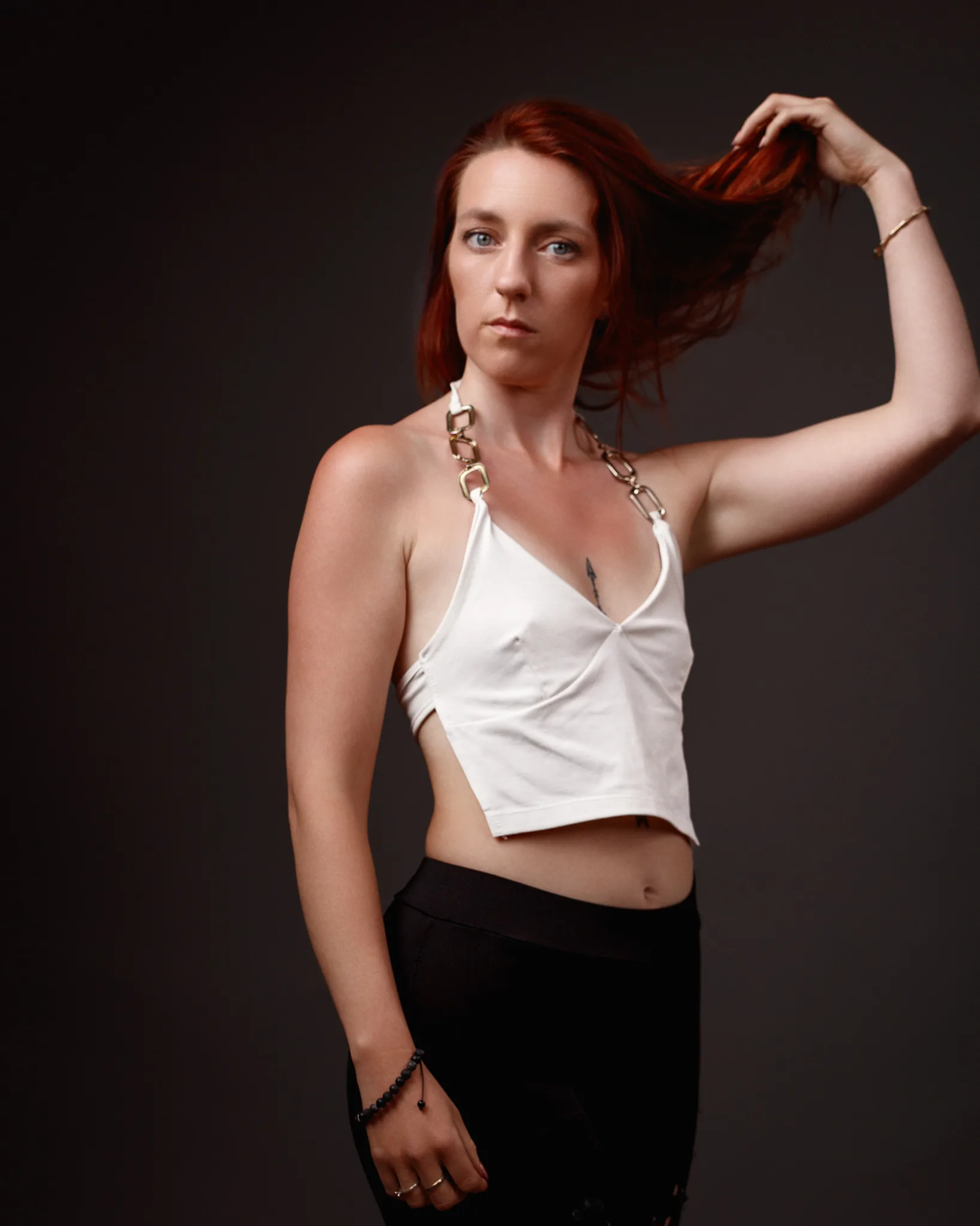 Woman with red hair posing against dark background