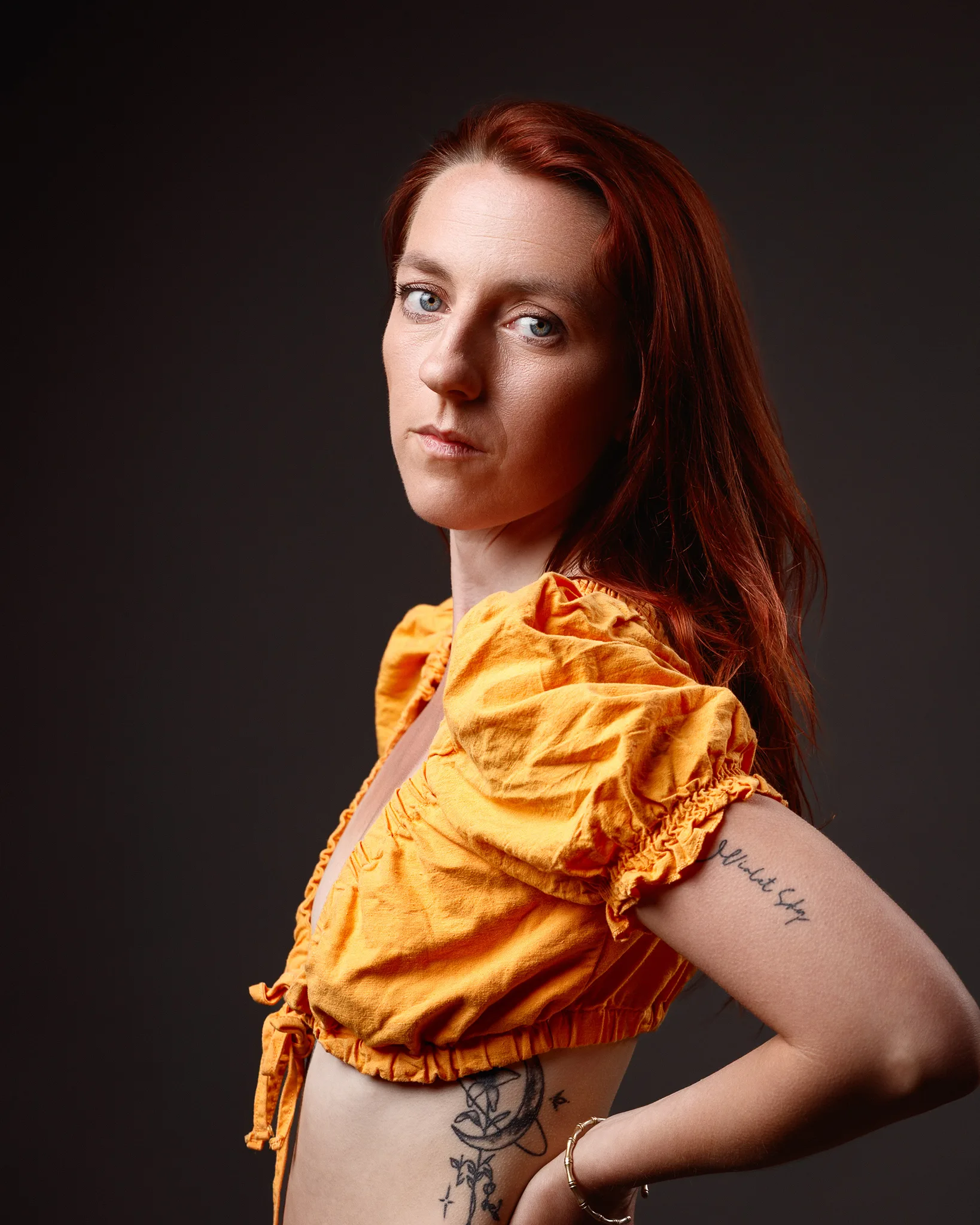 Red-haired woman in orange top, studio portrait