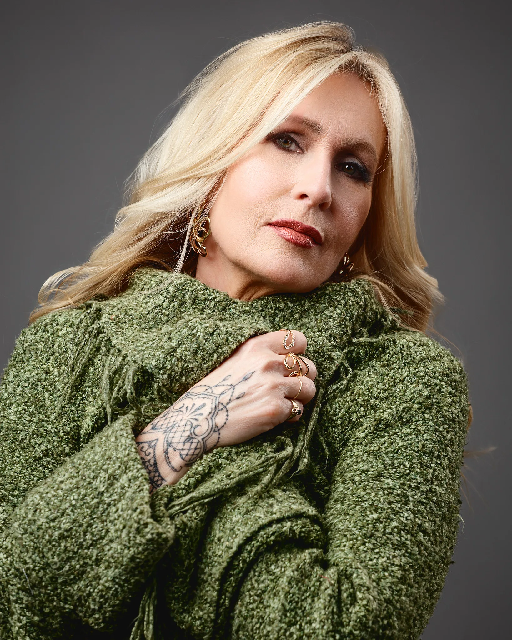 Blonde woman in green jumper with gold jewellery