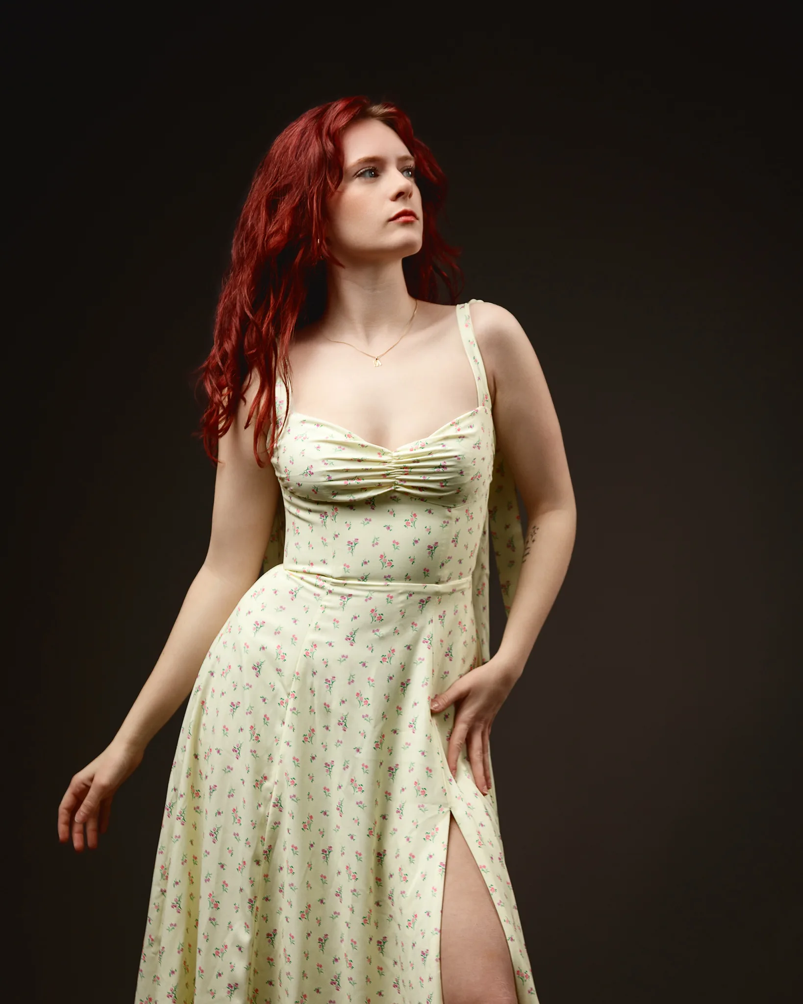 Red-haired woman in floral dress against dark backdrop