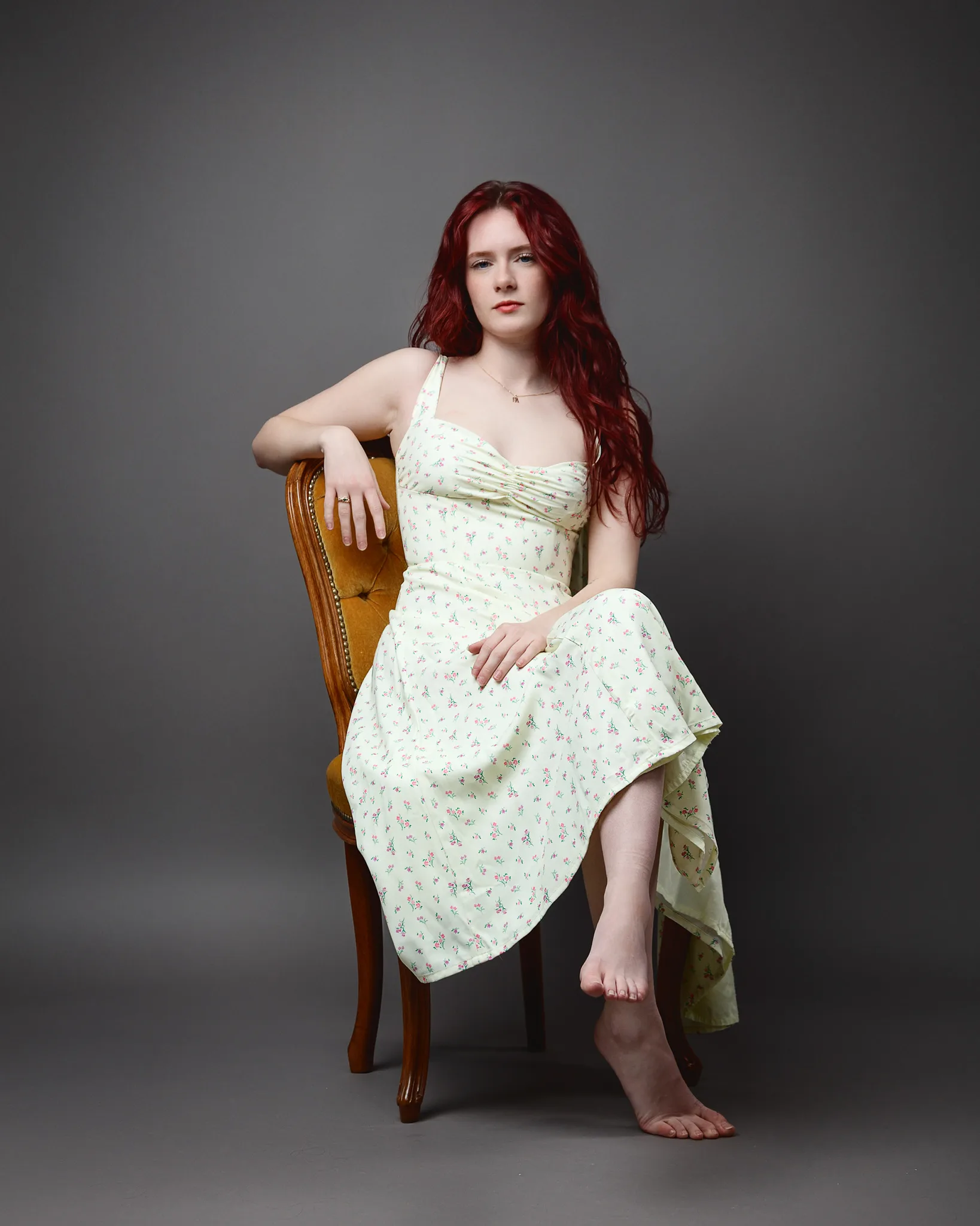 Red-haired woman in floral dress seated on chair