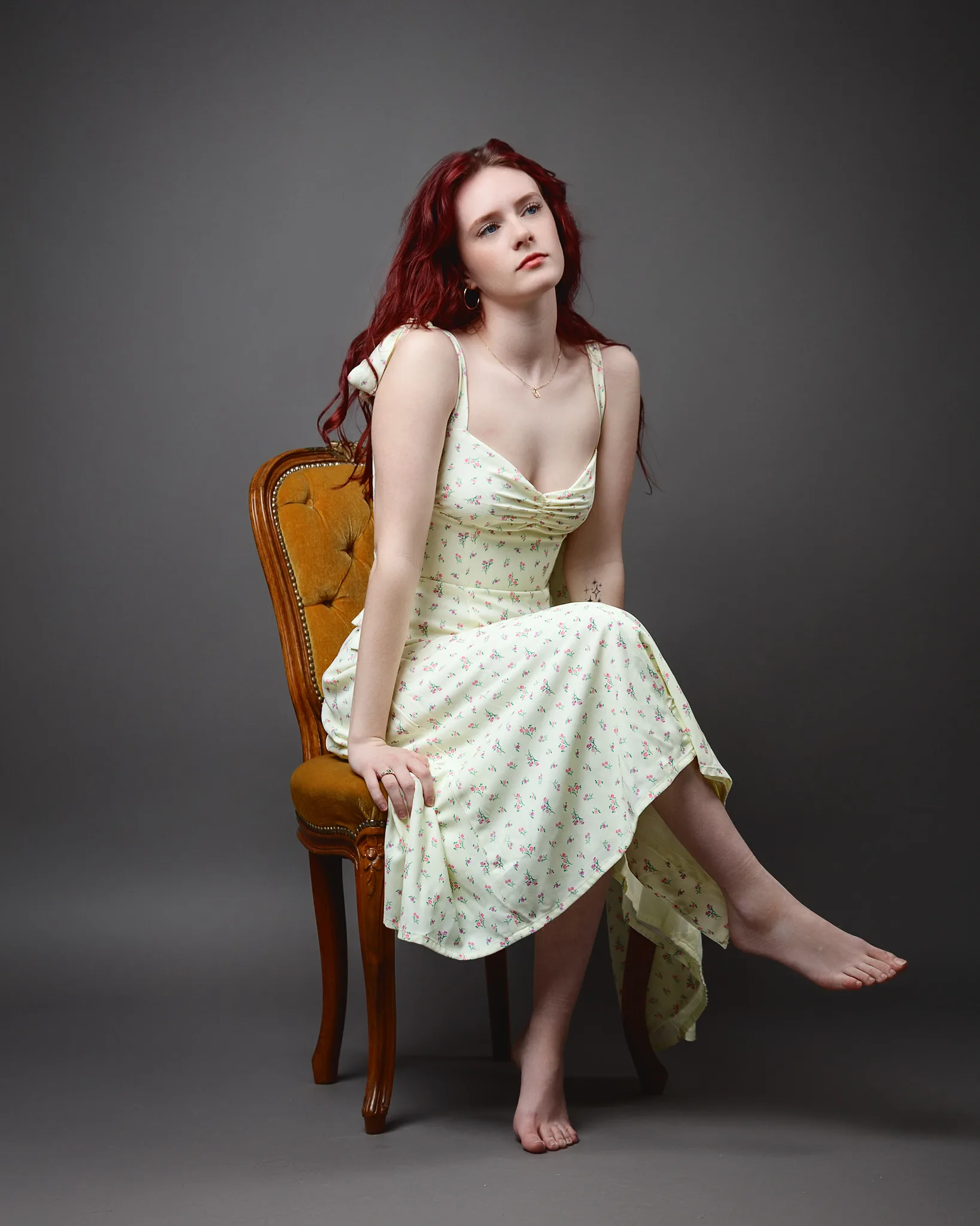 Red-haired woman in floral dress seated on chair