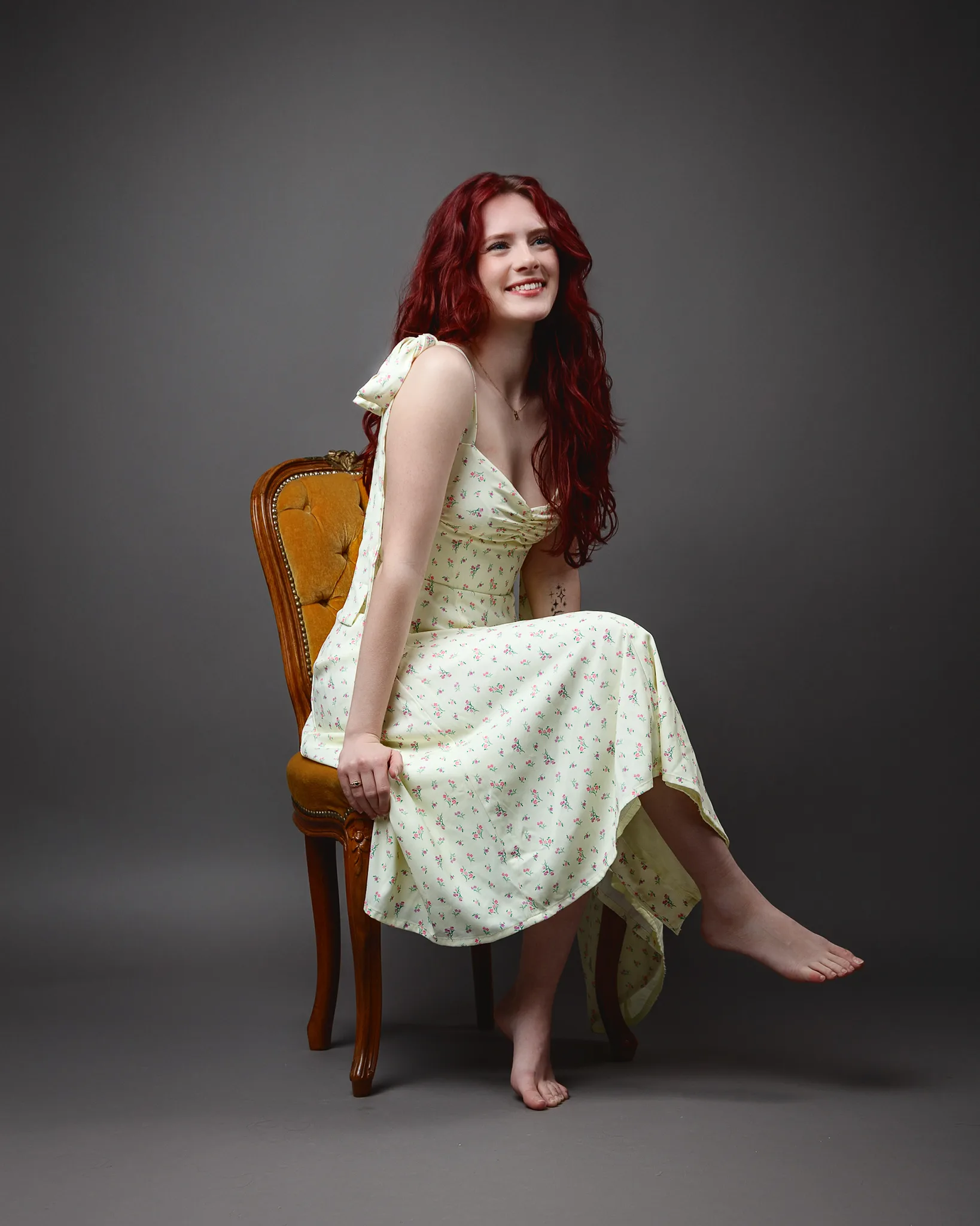 Red-haired woman in floral dress on chair