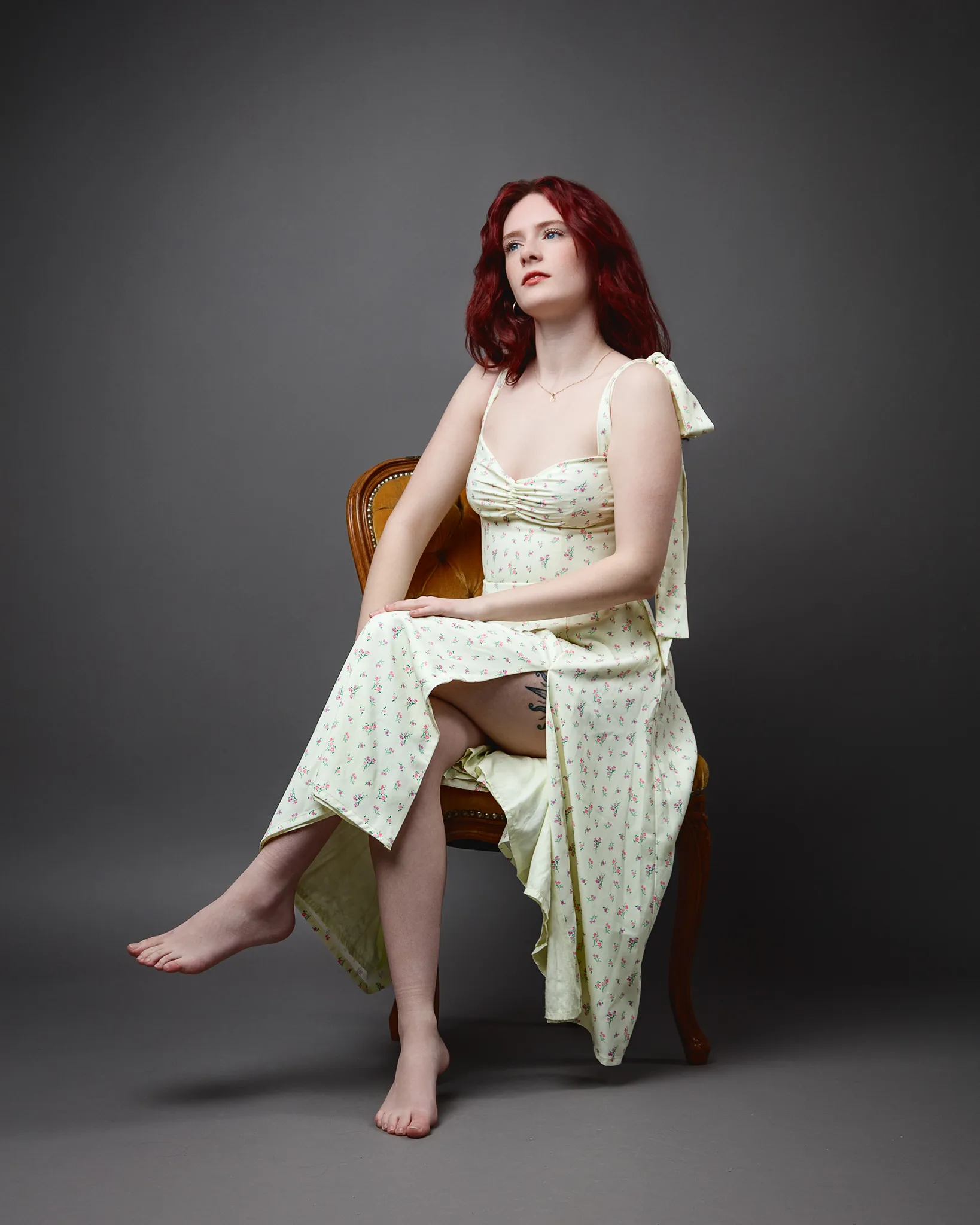 Red-haired woman in floral dress seated barefoot