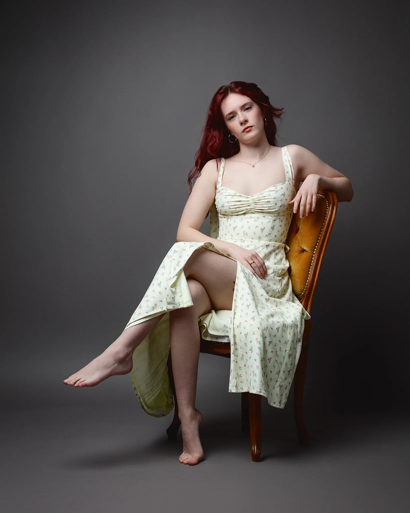 Red-haired woman in floral dress seated on chair