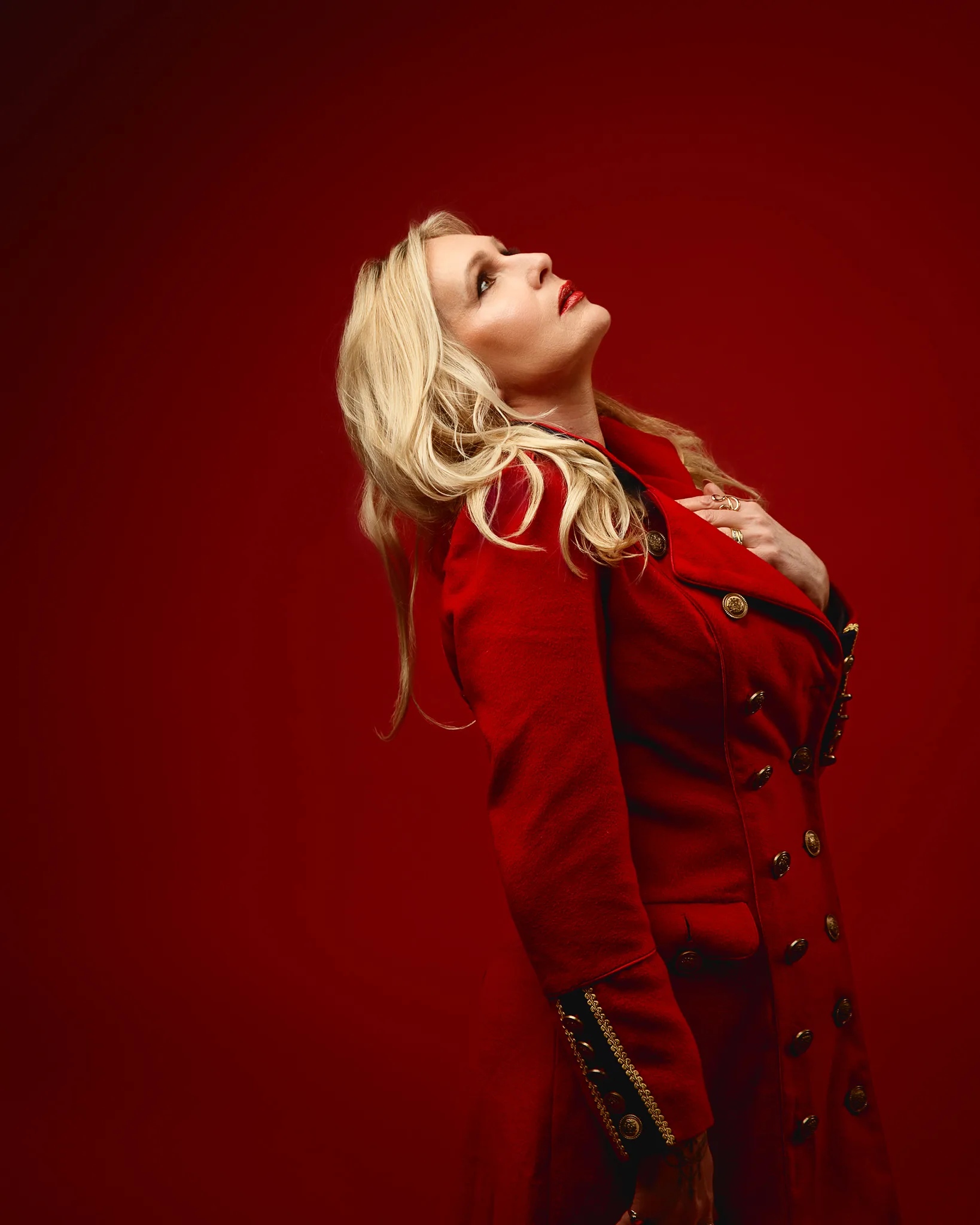 Blonde woman in red coat against red background