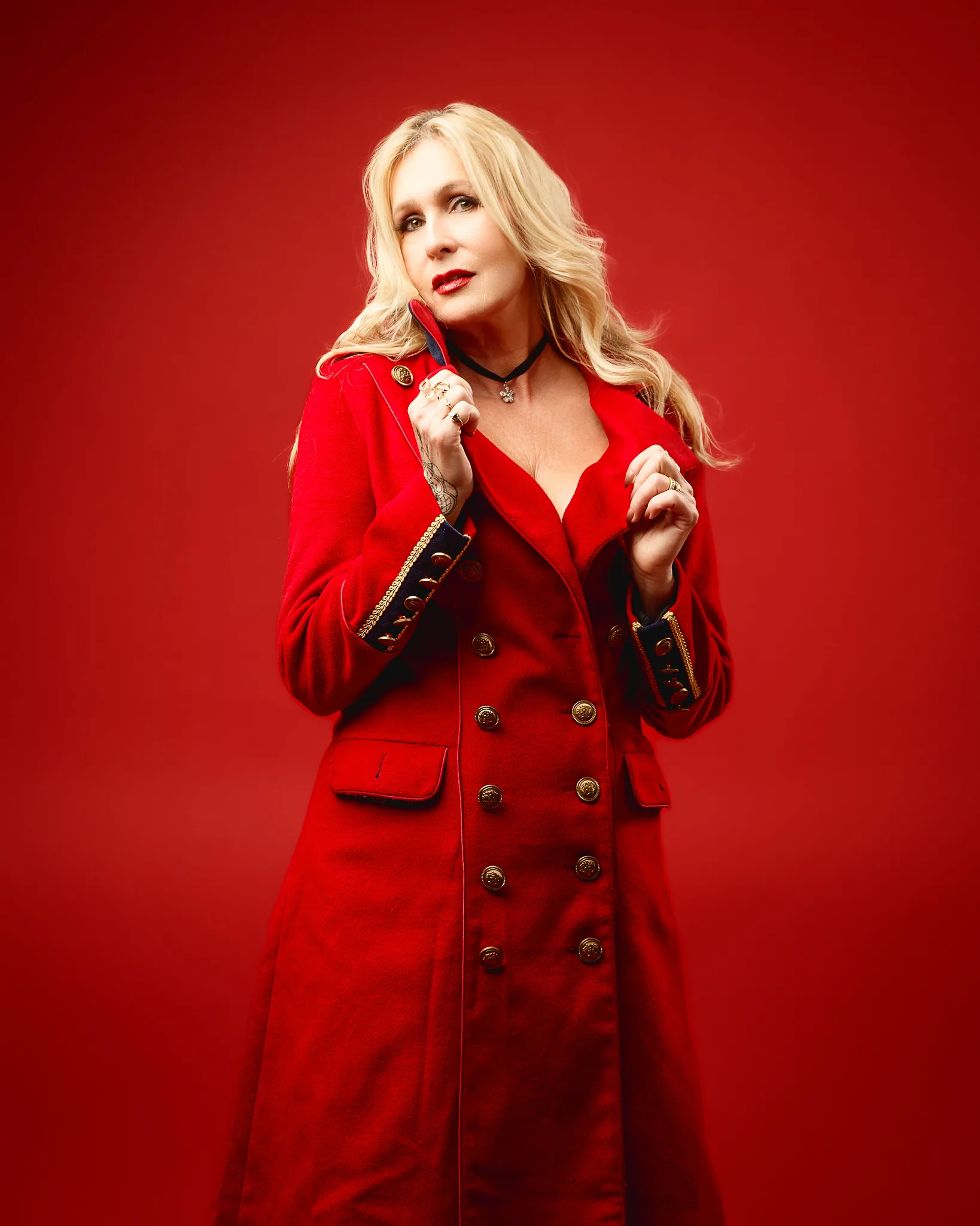 Blonde woman in red coat against red background