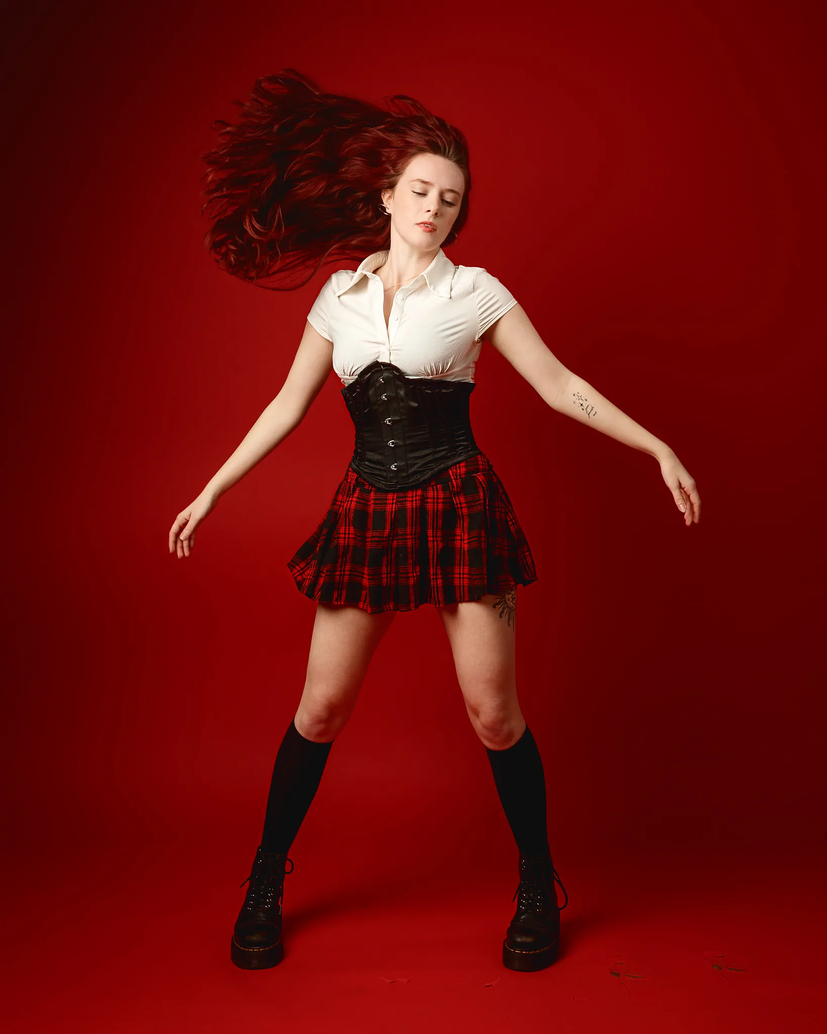 Woman in tartan skirt against red background