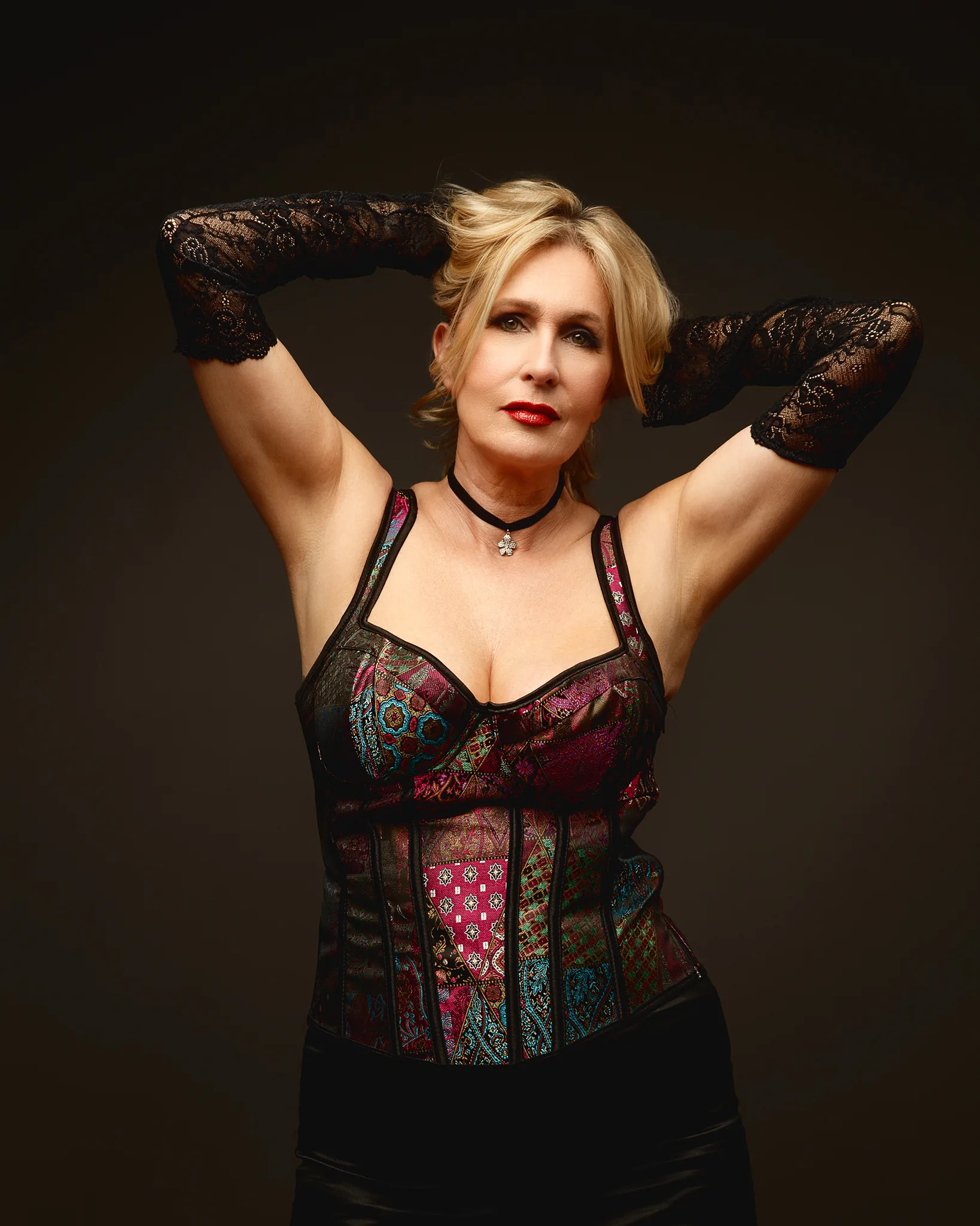 Woman in patterned corset and lace gloves posing
