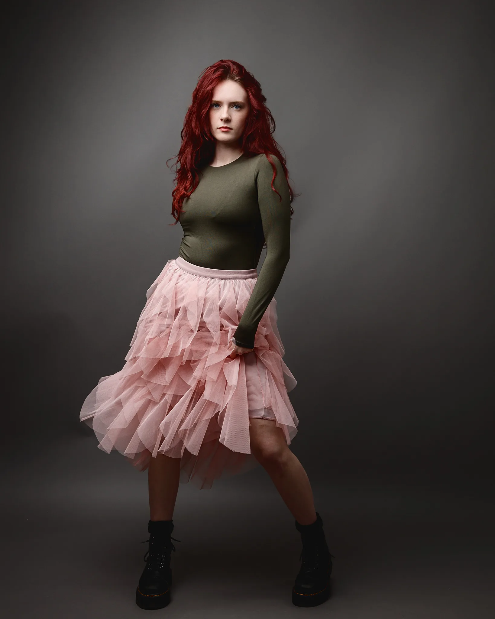 Red-haired woman in green top and pink skirt