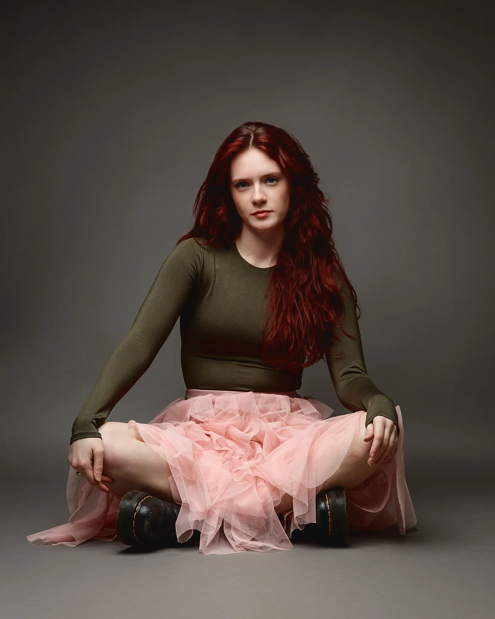 Red-haired woman in pink skirt sitting cross-legged