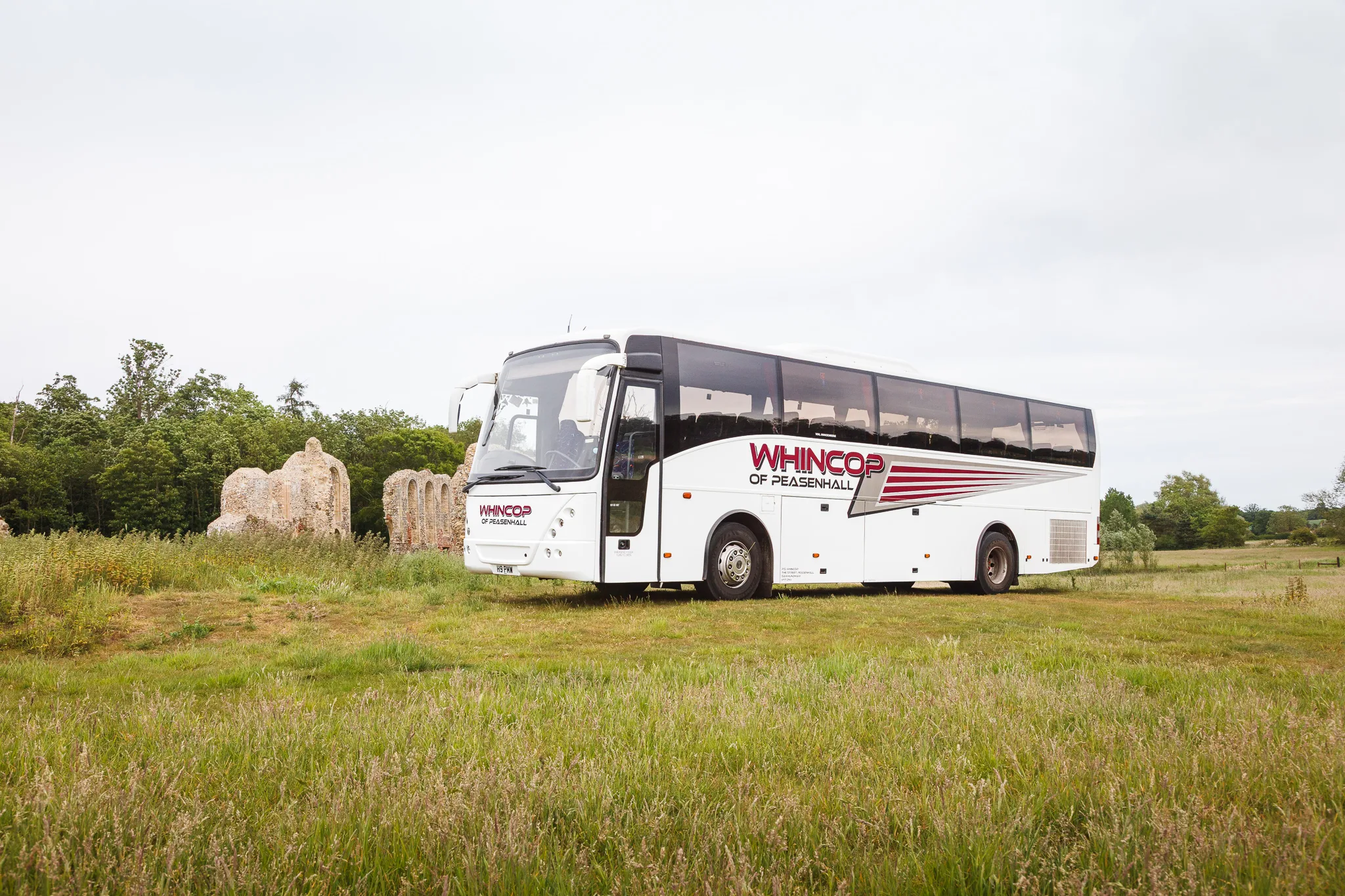 White coach parked beside historic stone ruins