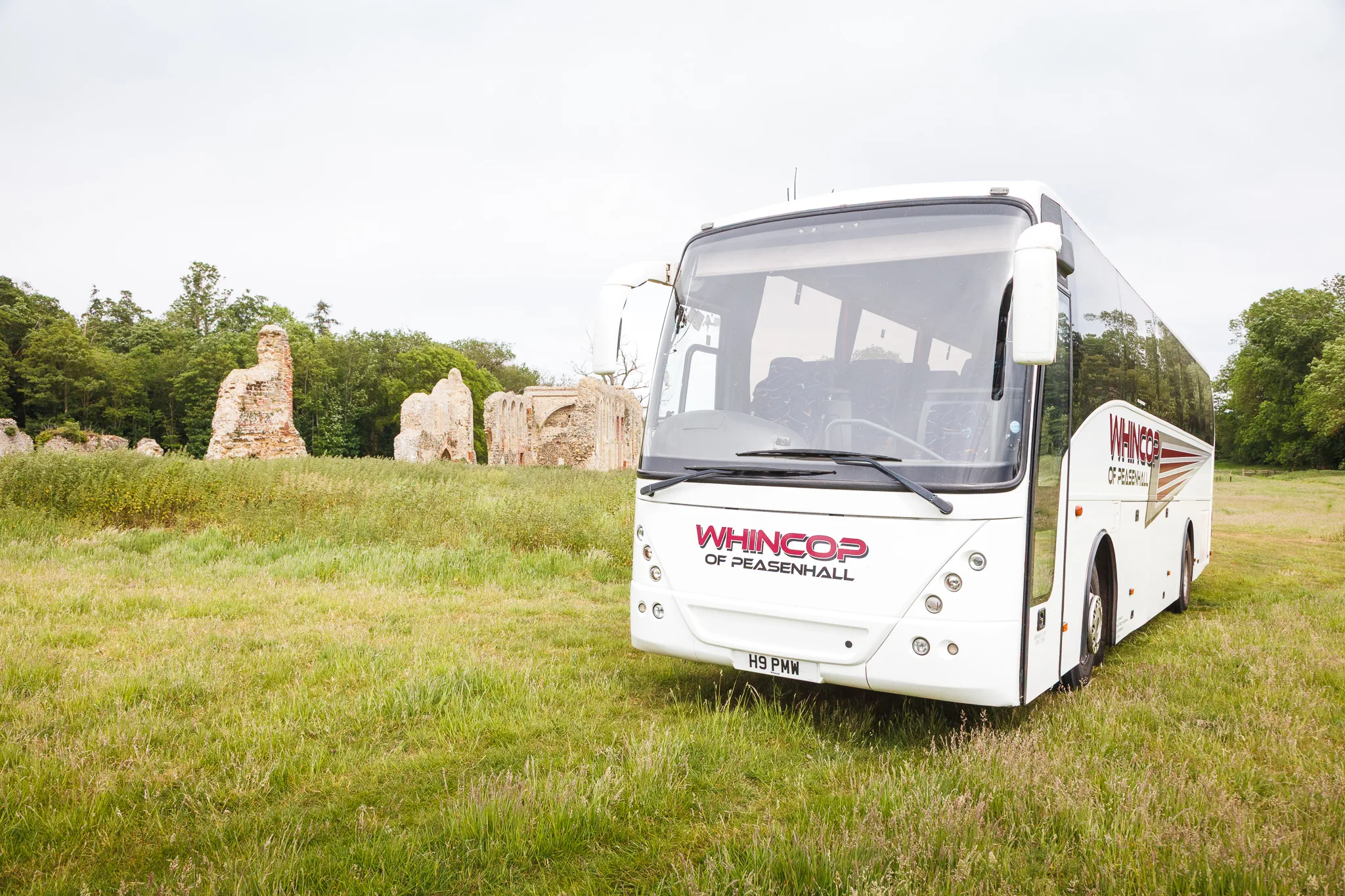 White coach parked beside historic abbey ruins