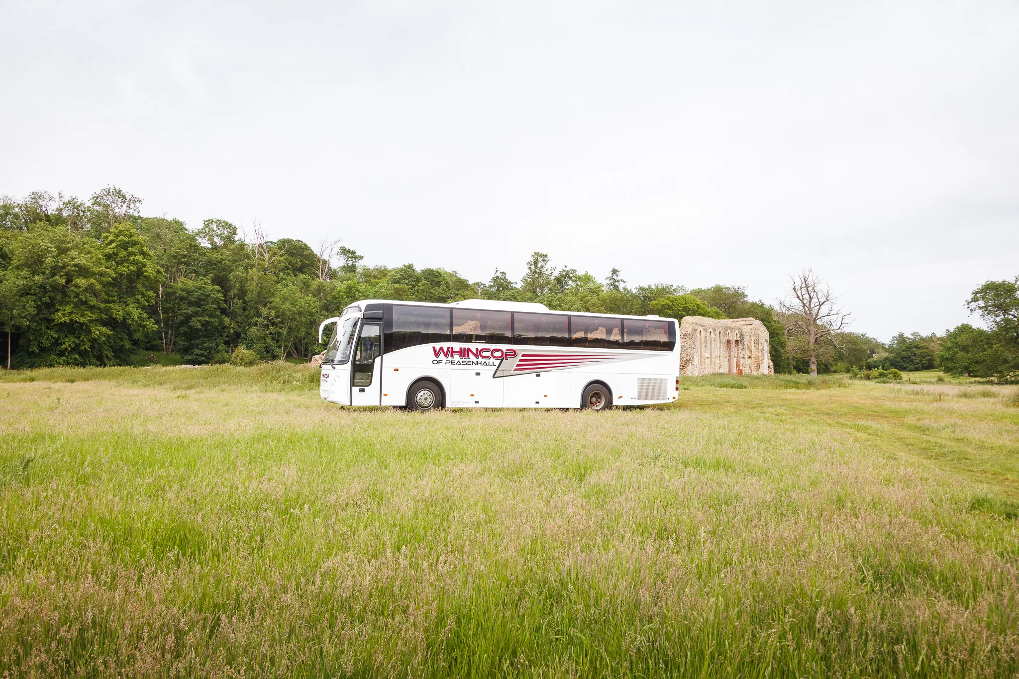 White coach parked in grassy countryside field