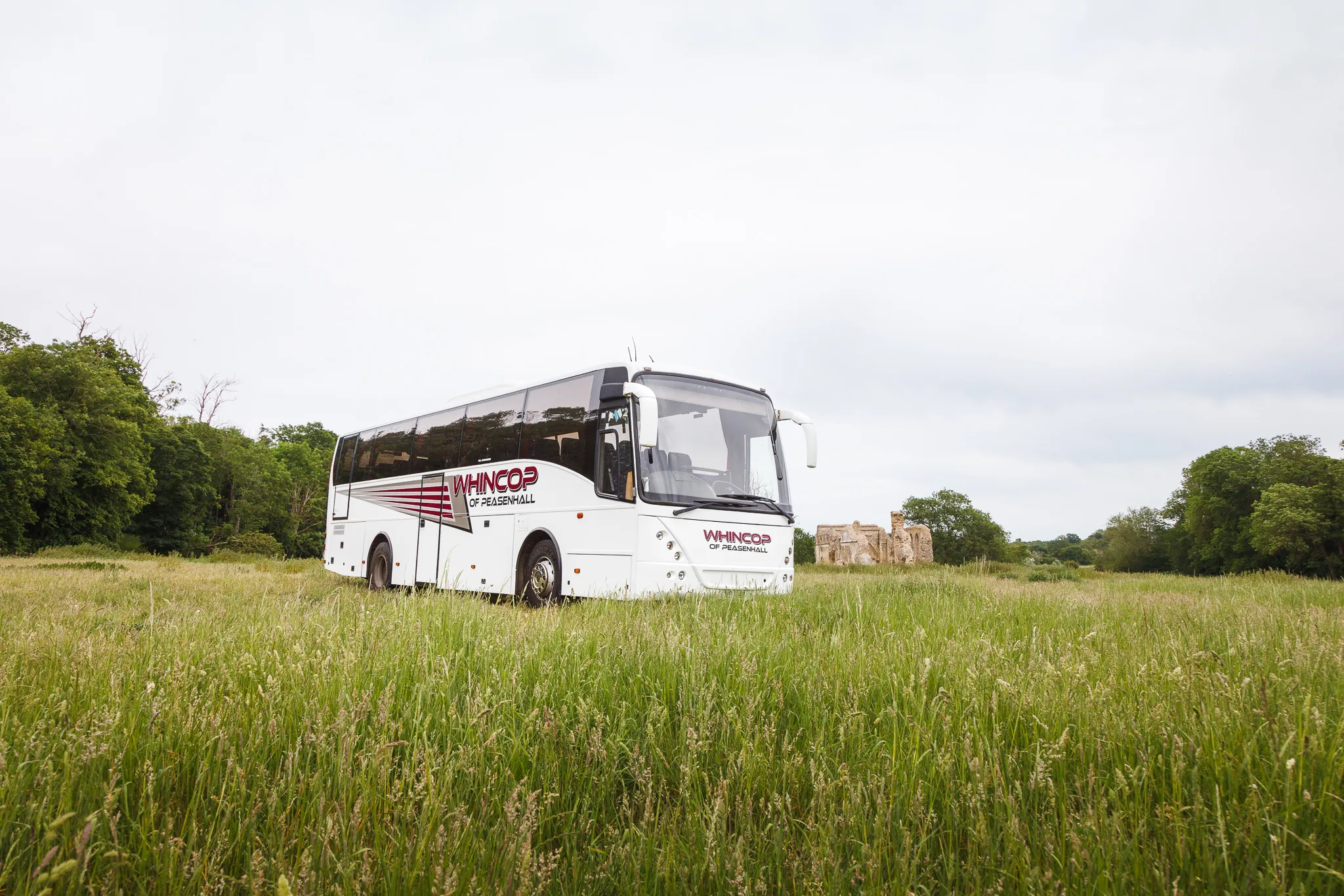 White coach parked in grassy countryside field