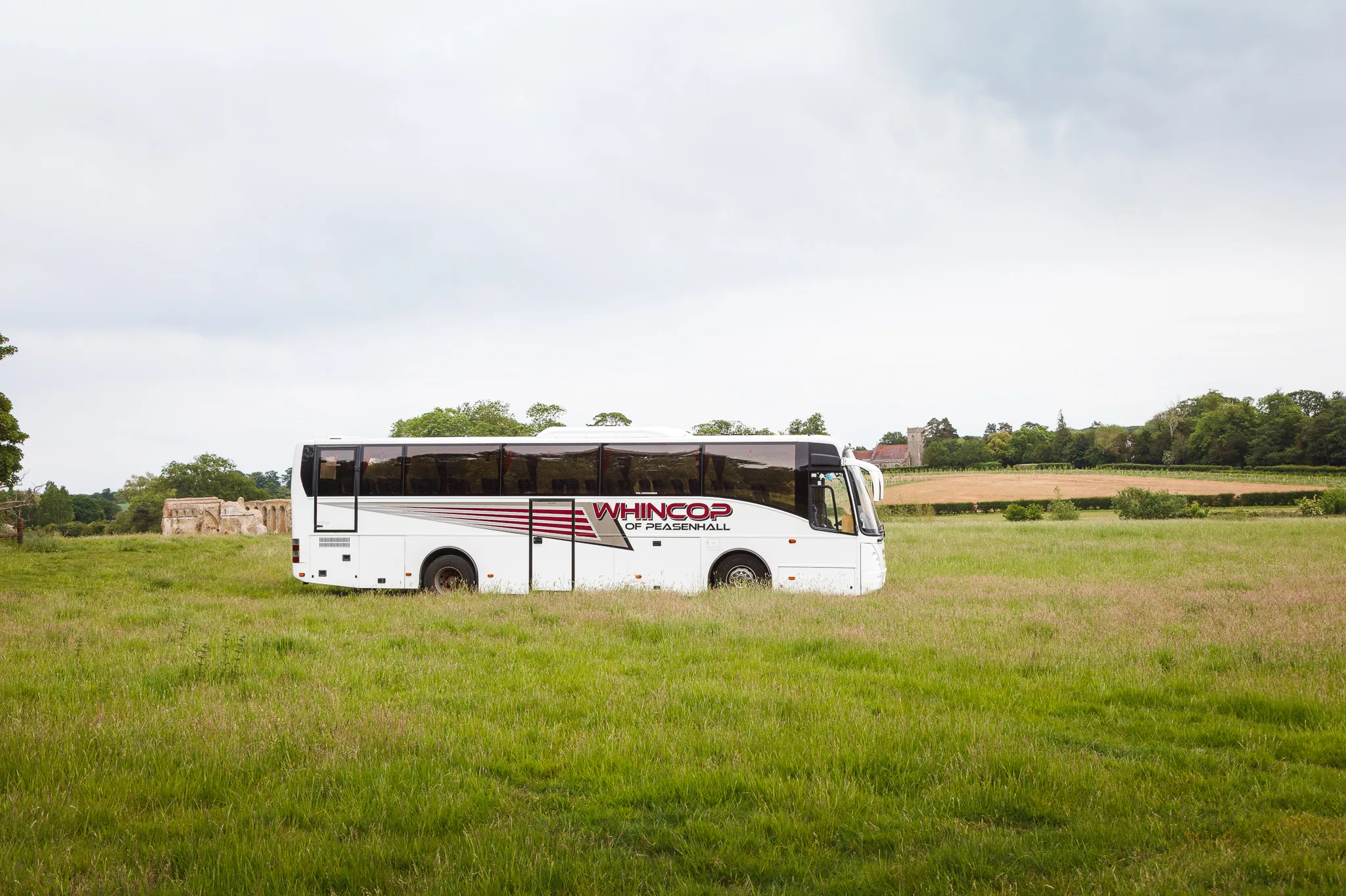 White coach parked in rural grassy field