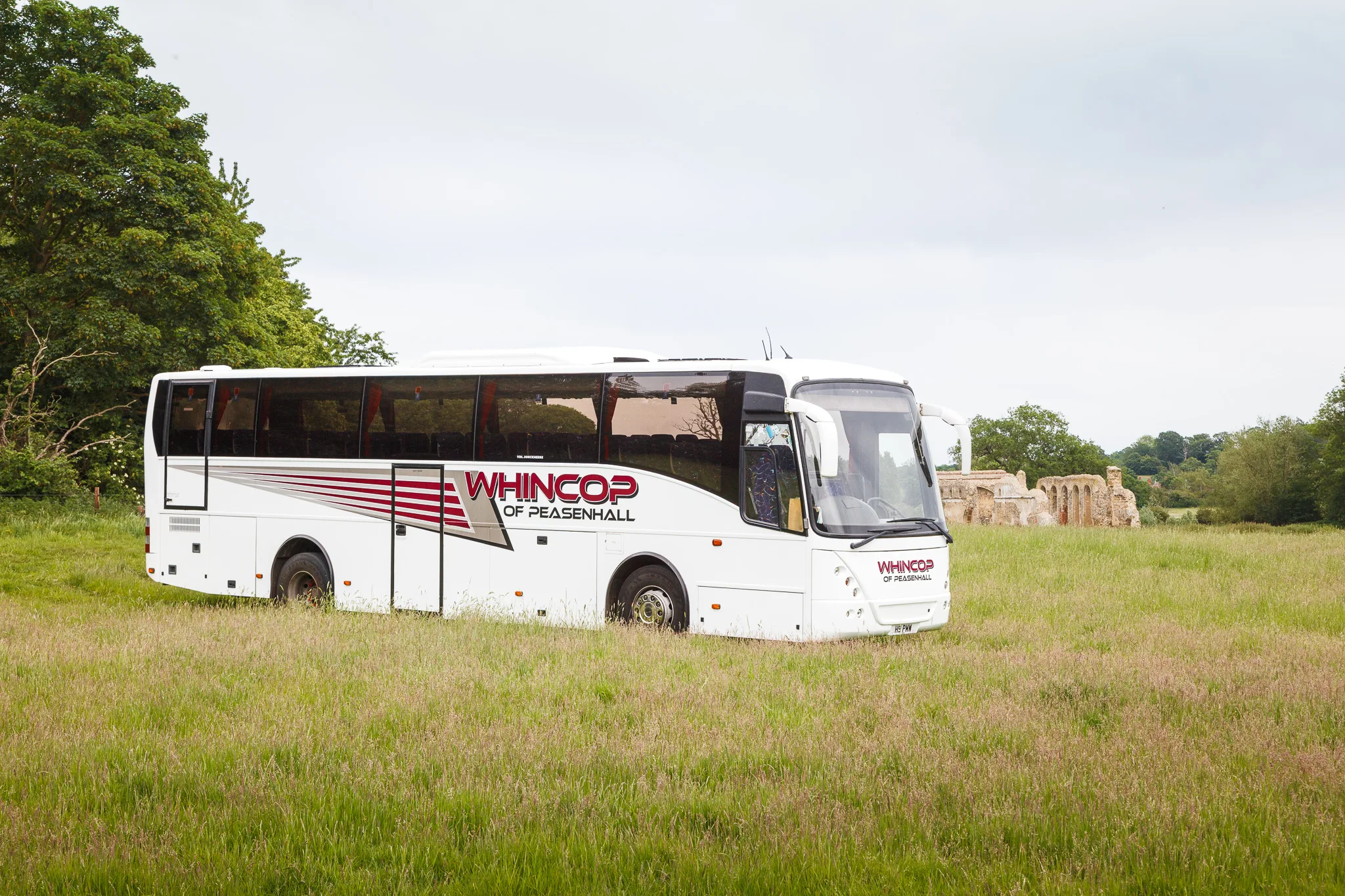 White coach parked in grassy countryside field