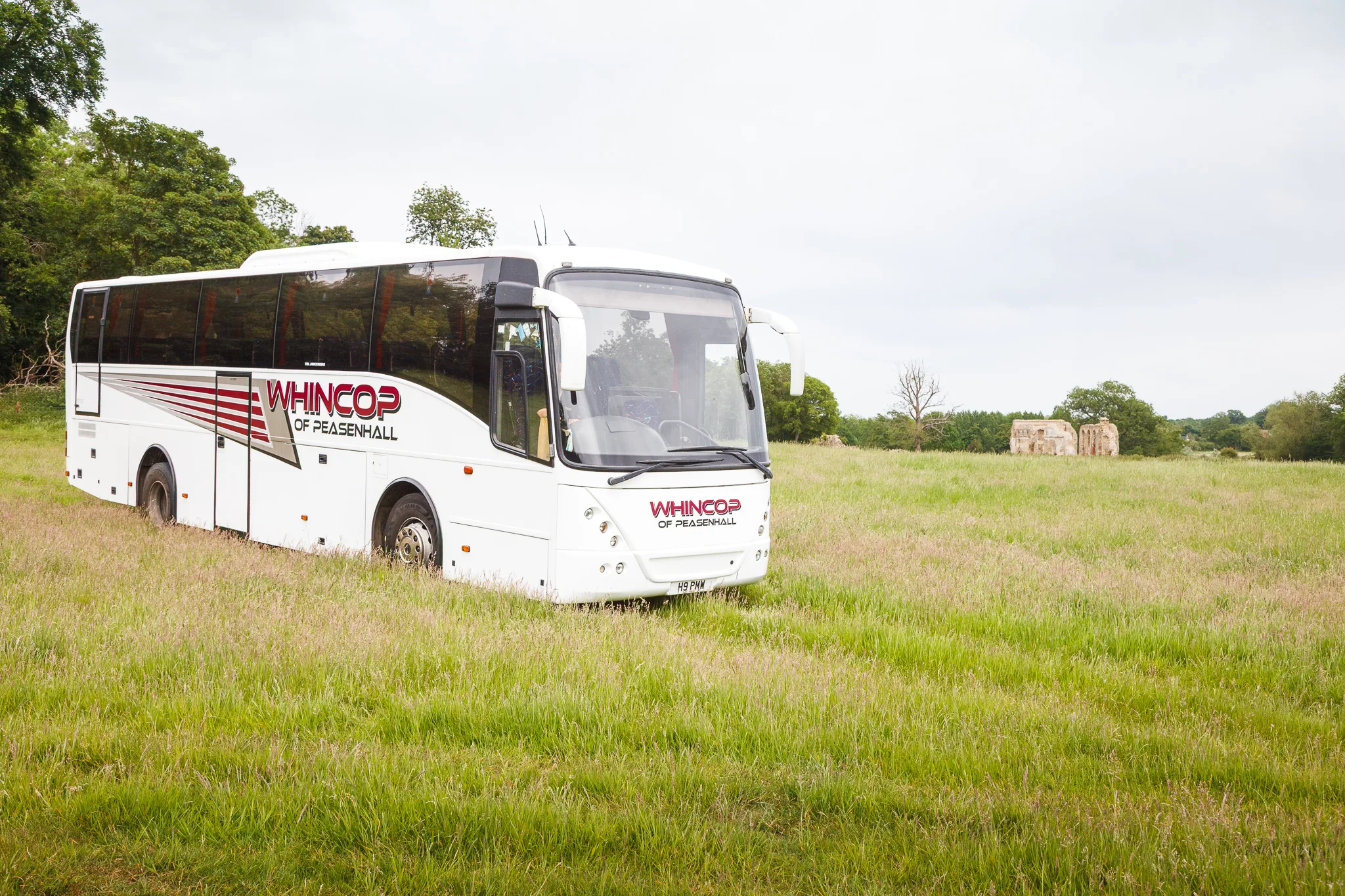 White coach parked in grassy countryside field
