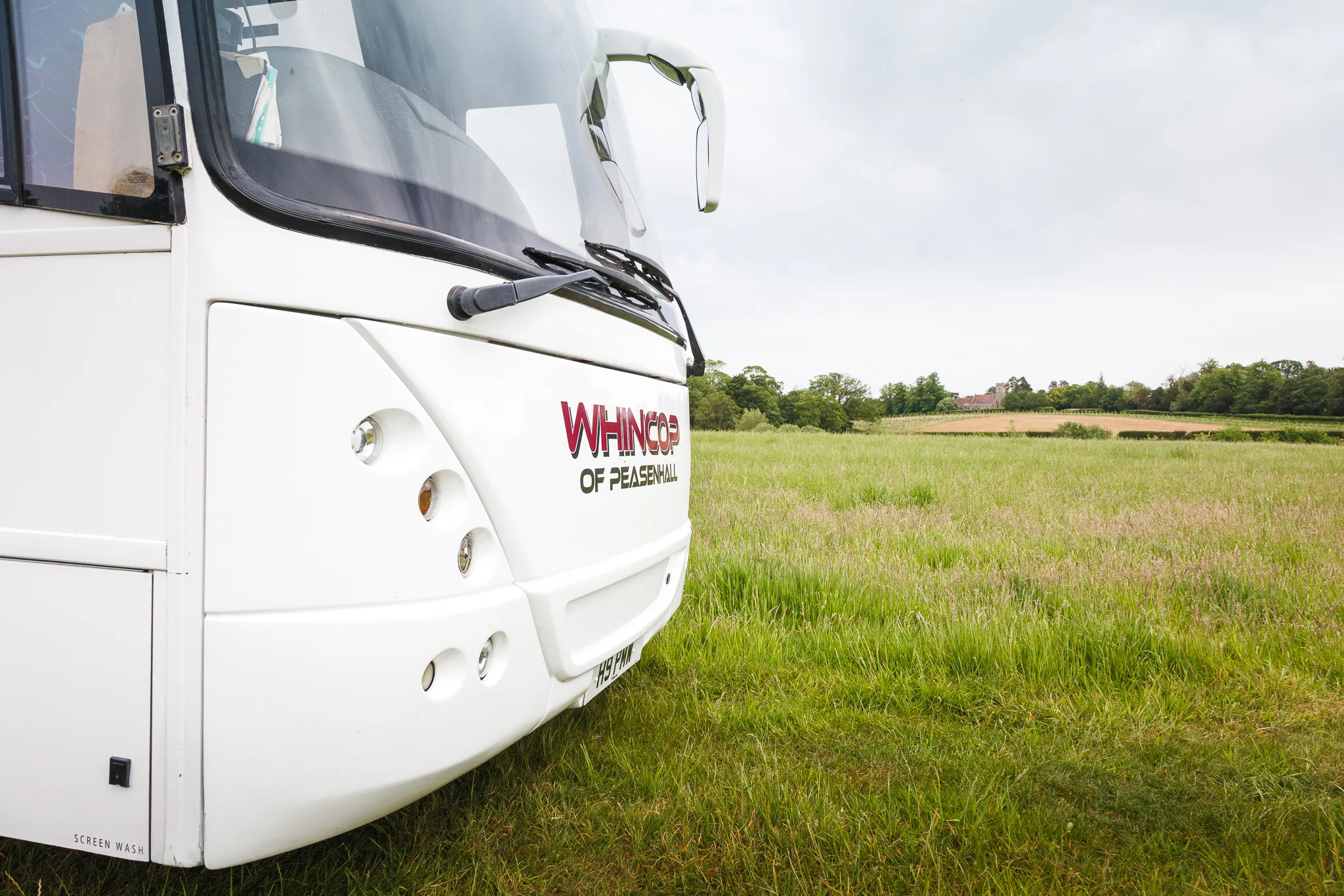 White coach parked in grassy countryside field