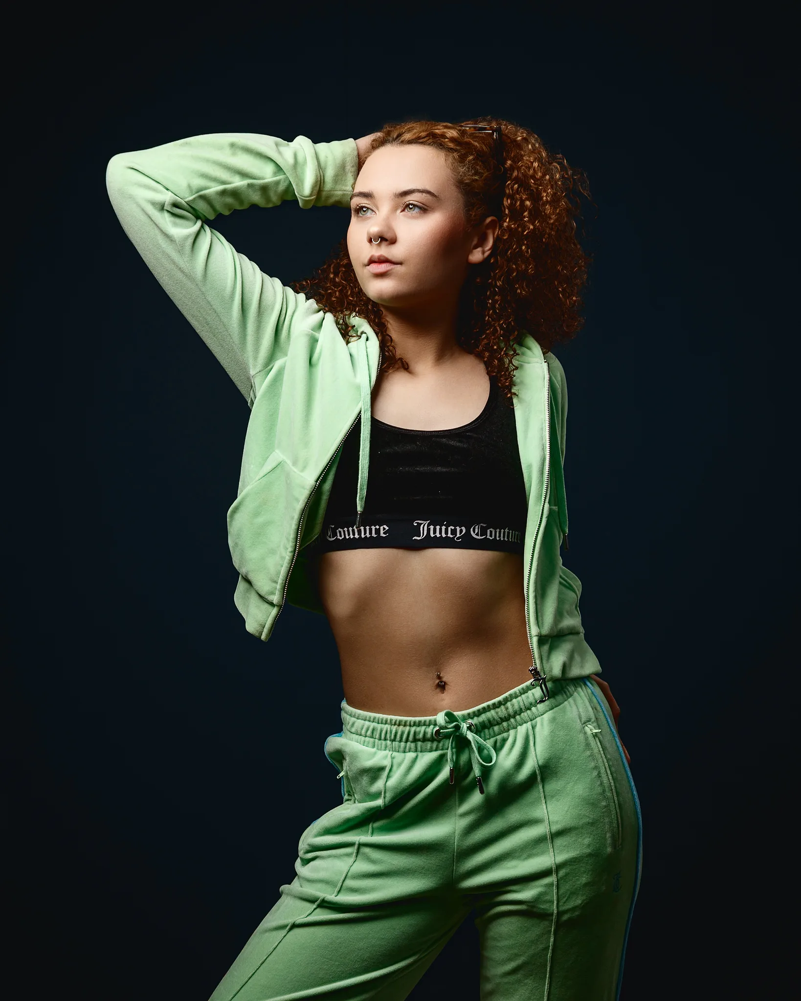 Young woman in green tracksuit posing in studio
