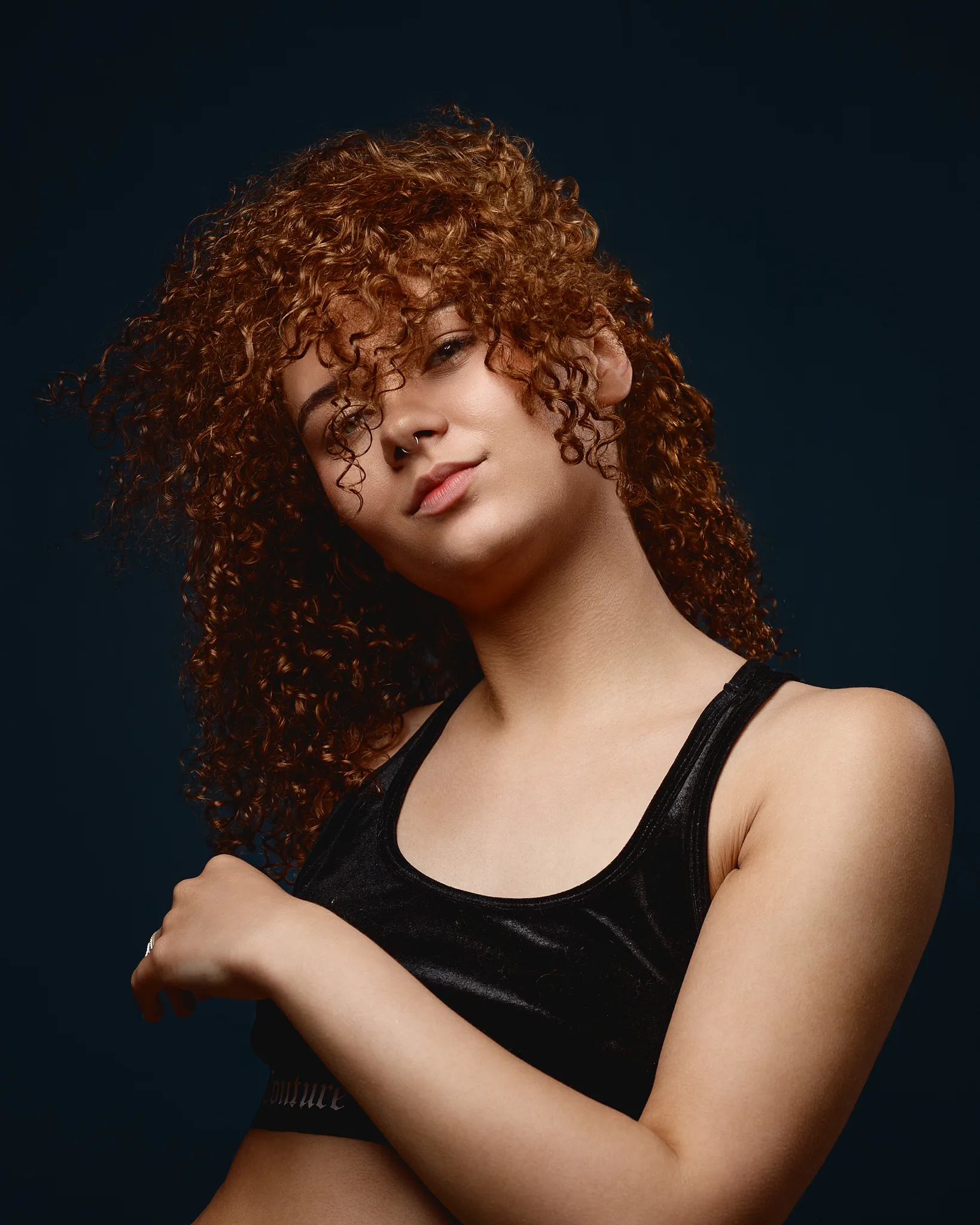 Woman with curly red hair against dark blue background