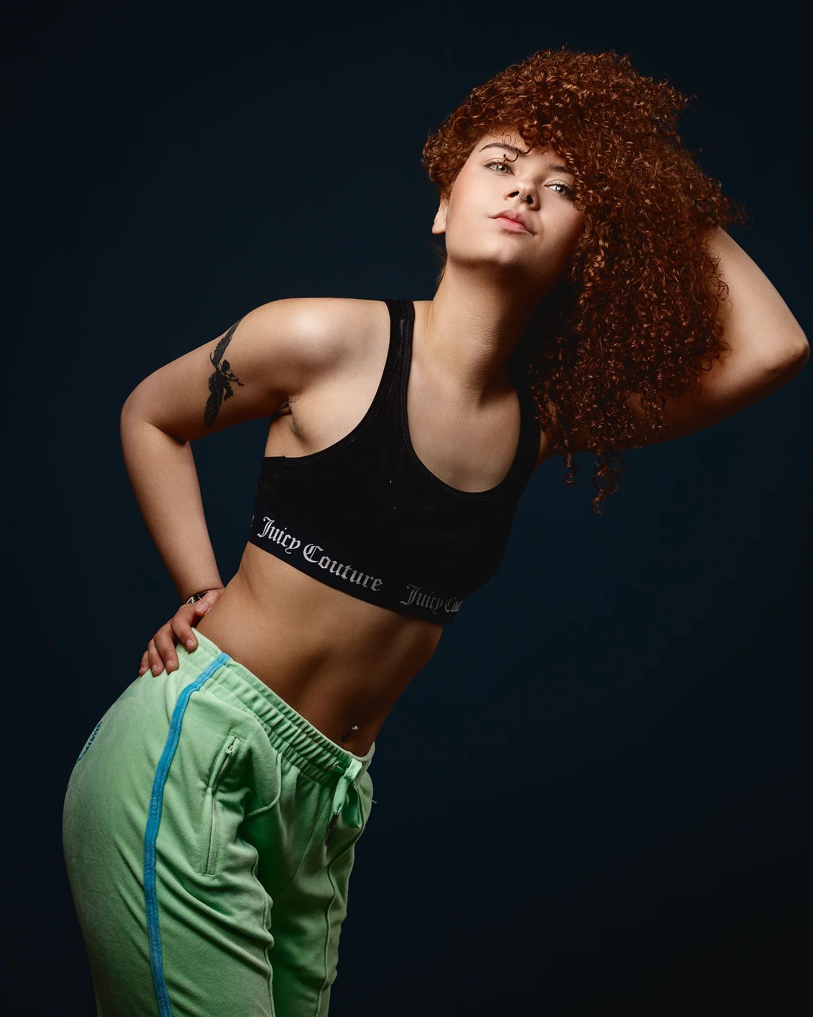 Woman with curly red hair in sportswear posing