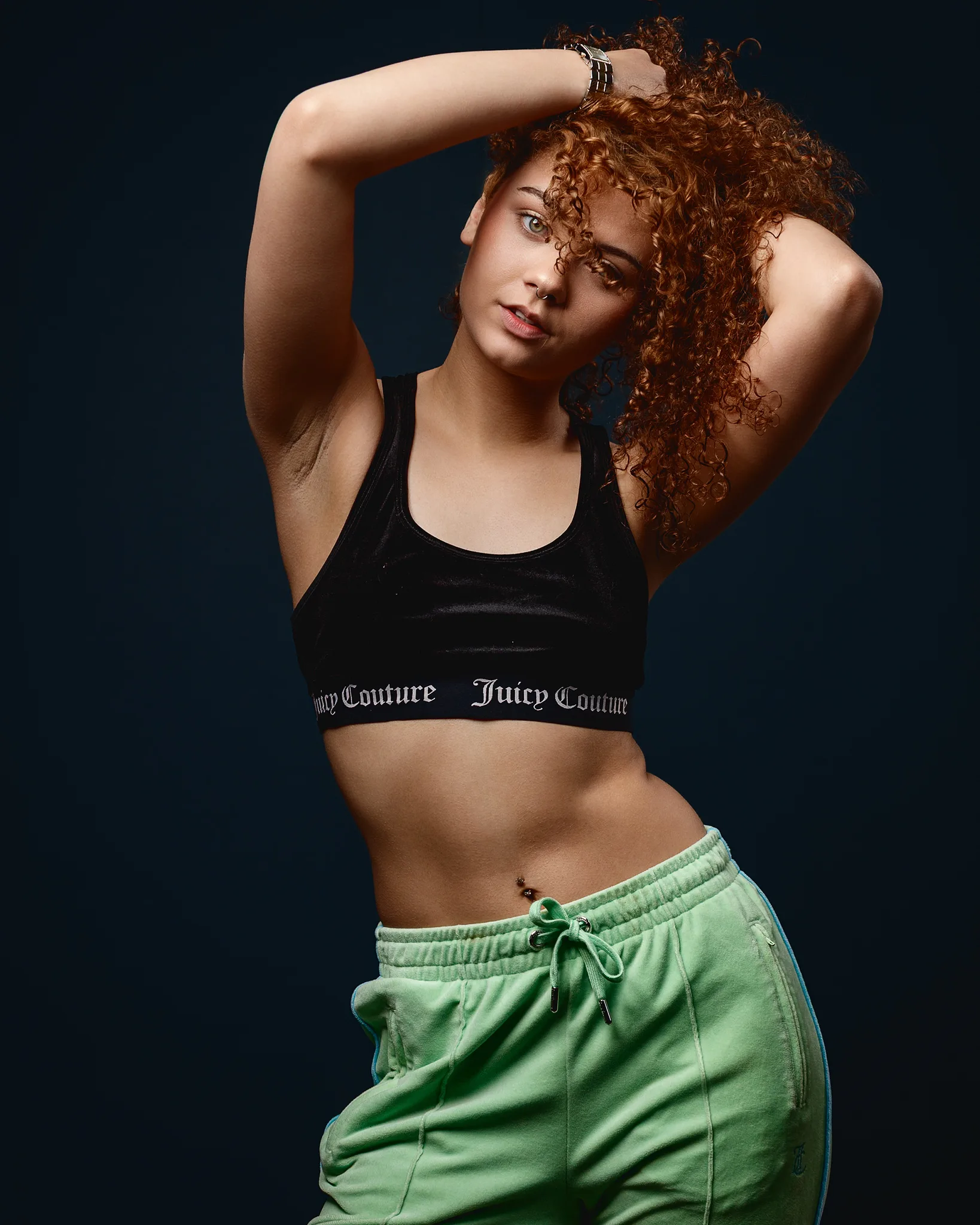 Woman with curly hair posing in sportswear studio