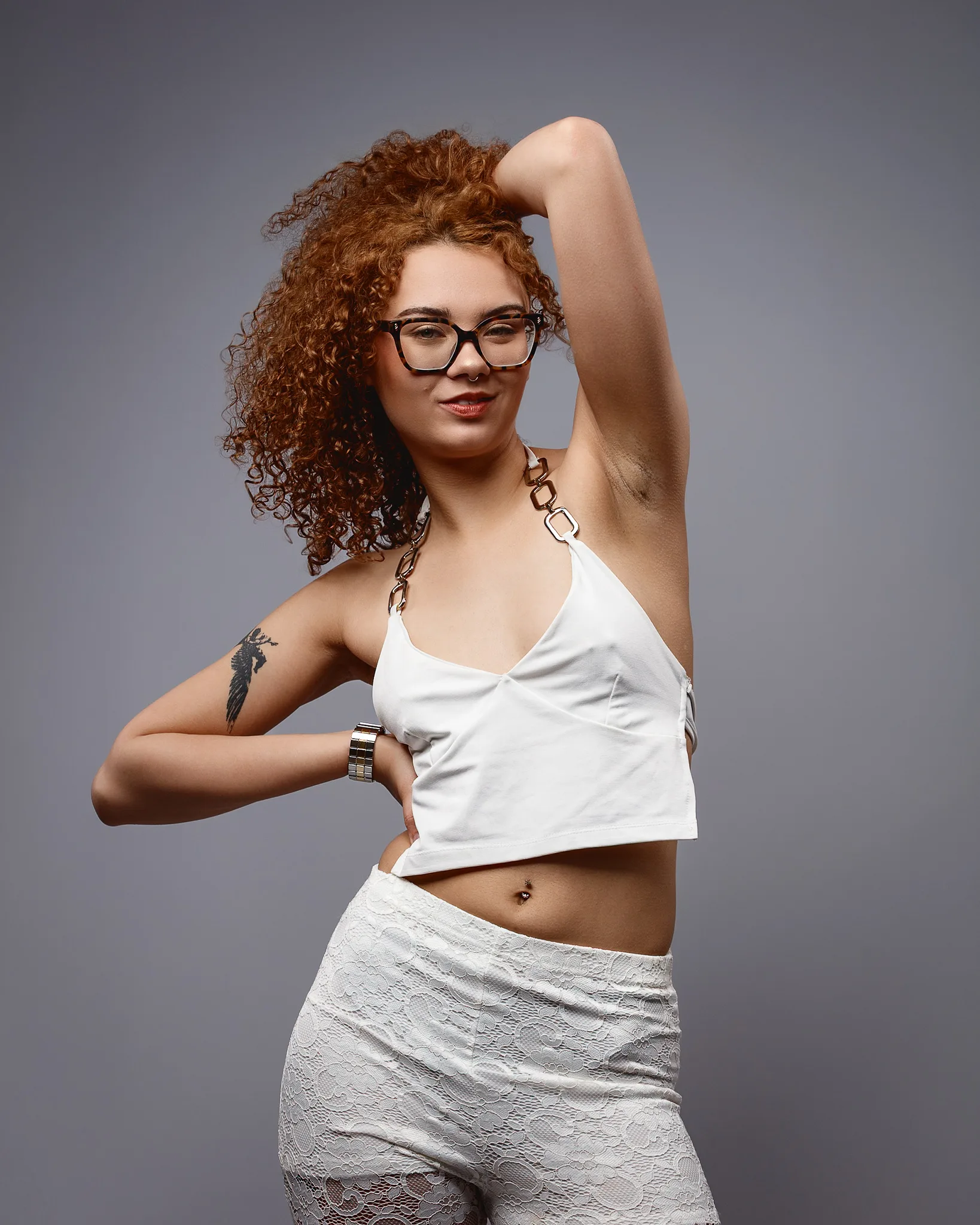 Woman with curly hair posing in white outfit