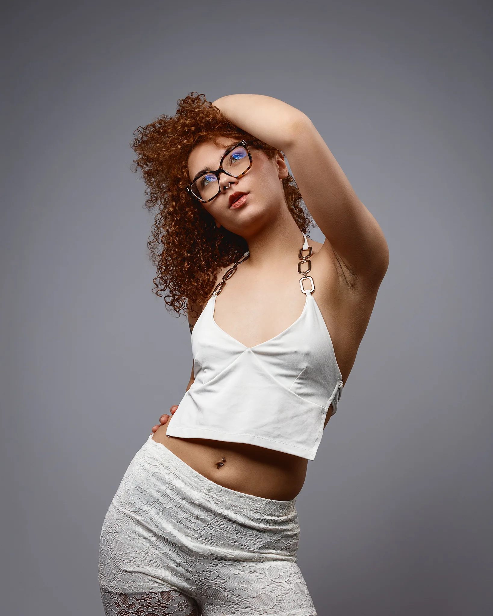 Woman with curly red hair posing in white outfit
