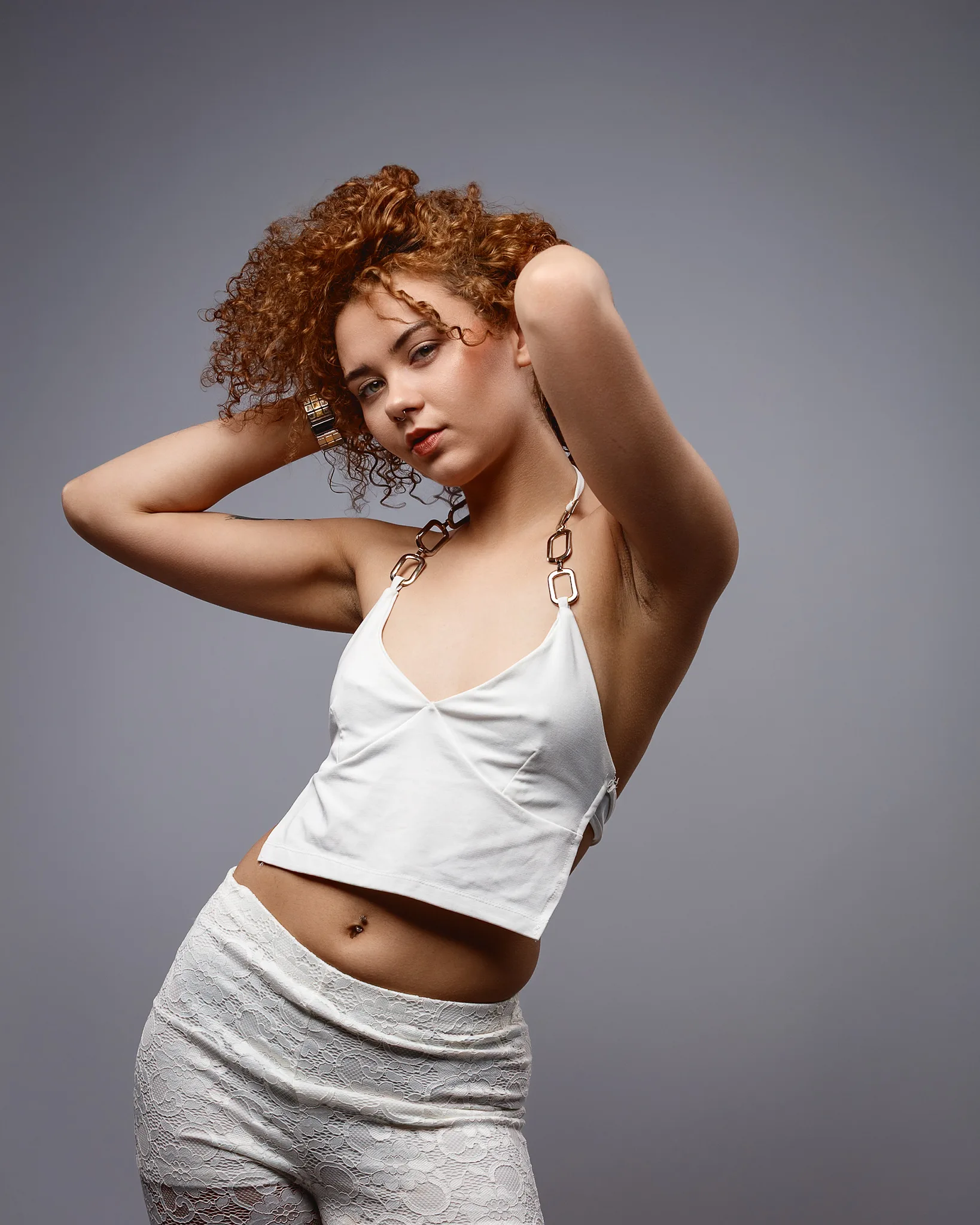 Woman with curly red hair posing in white outfit