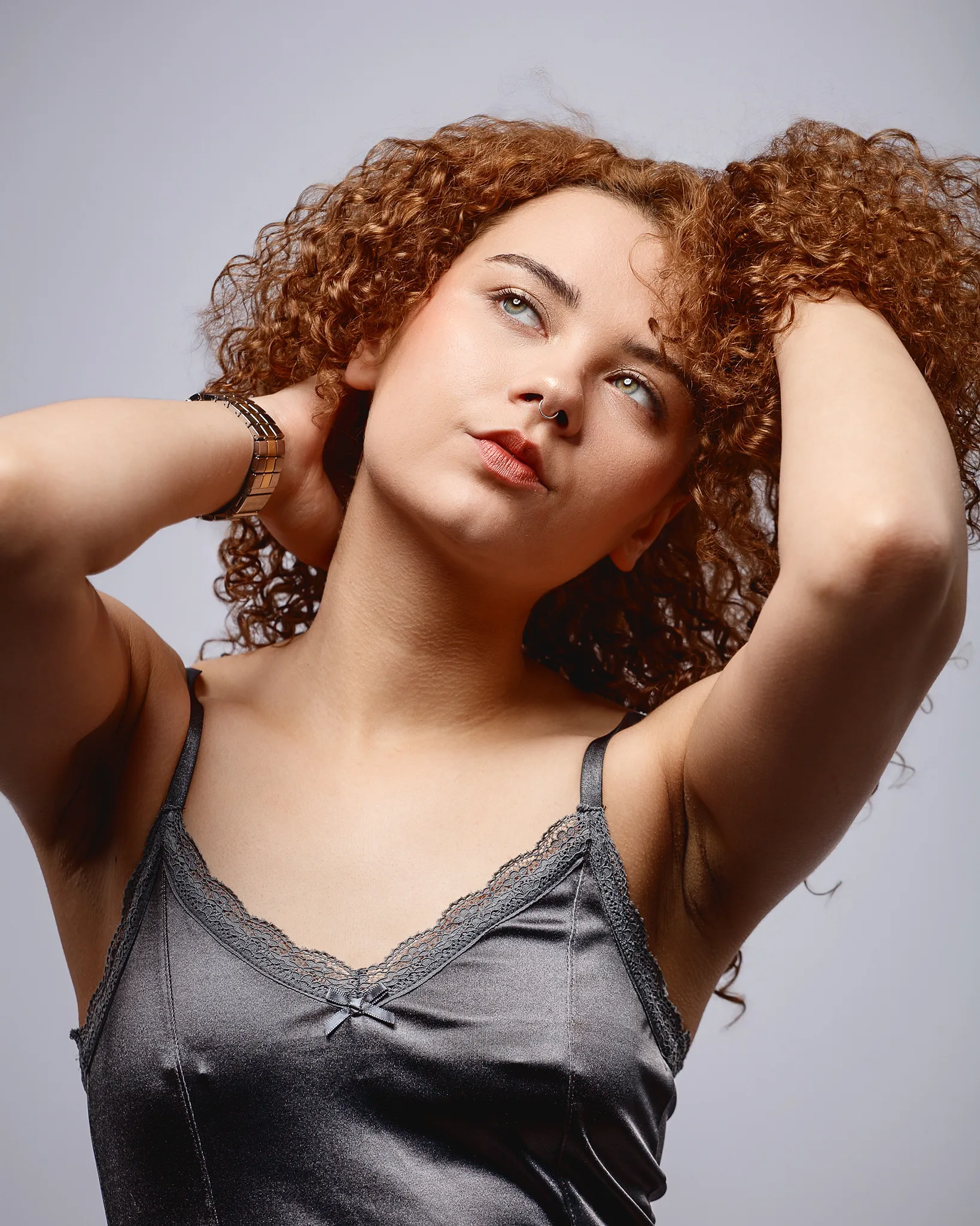 Woman with curly red hair and septum piercing