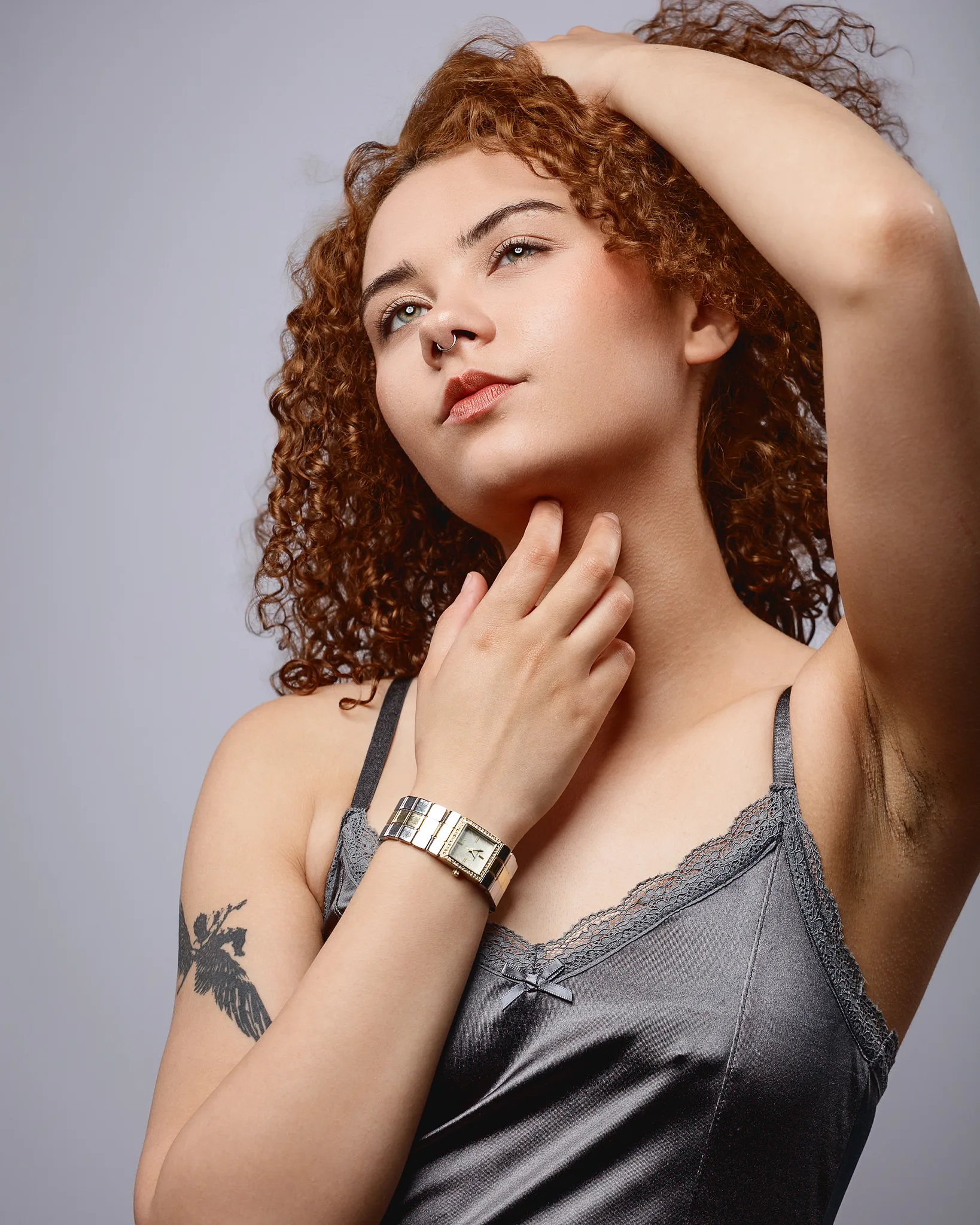 Woman with curly hair posing against neutral background