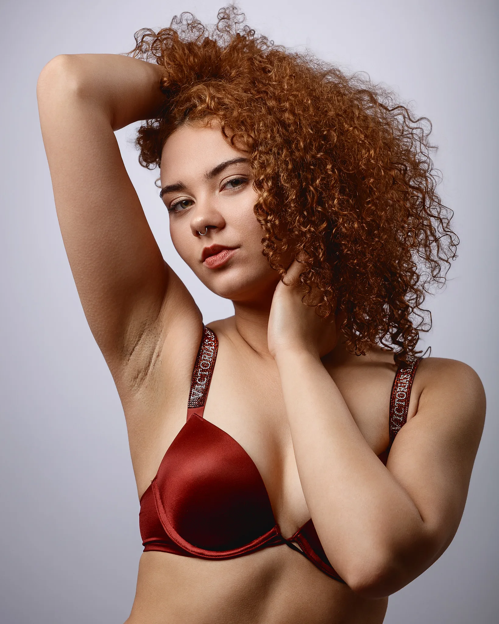 Woman with curly auburn hair wearing red lingerie