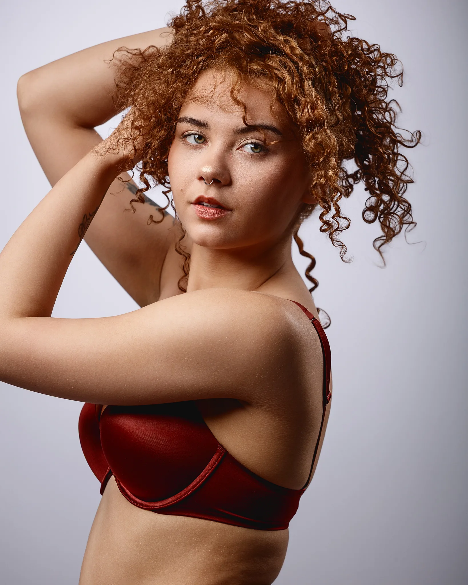 Woman with curly auburn hair wearing red sports bra
