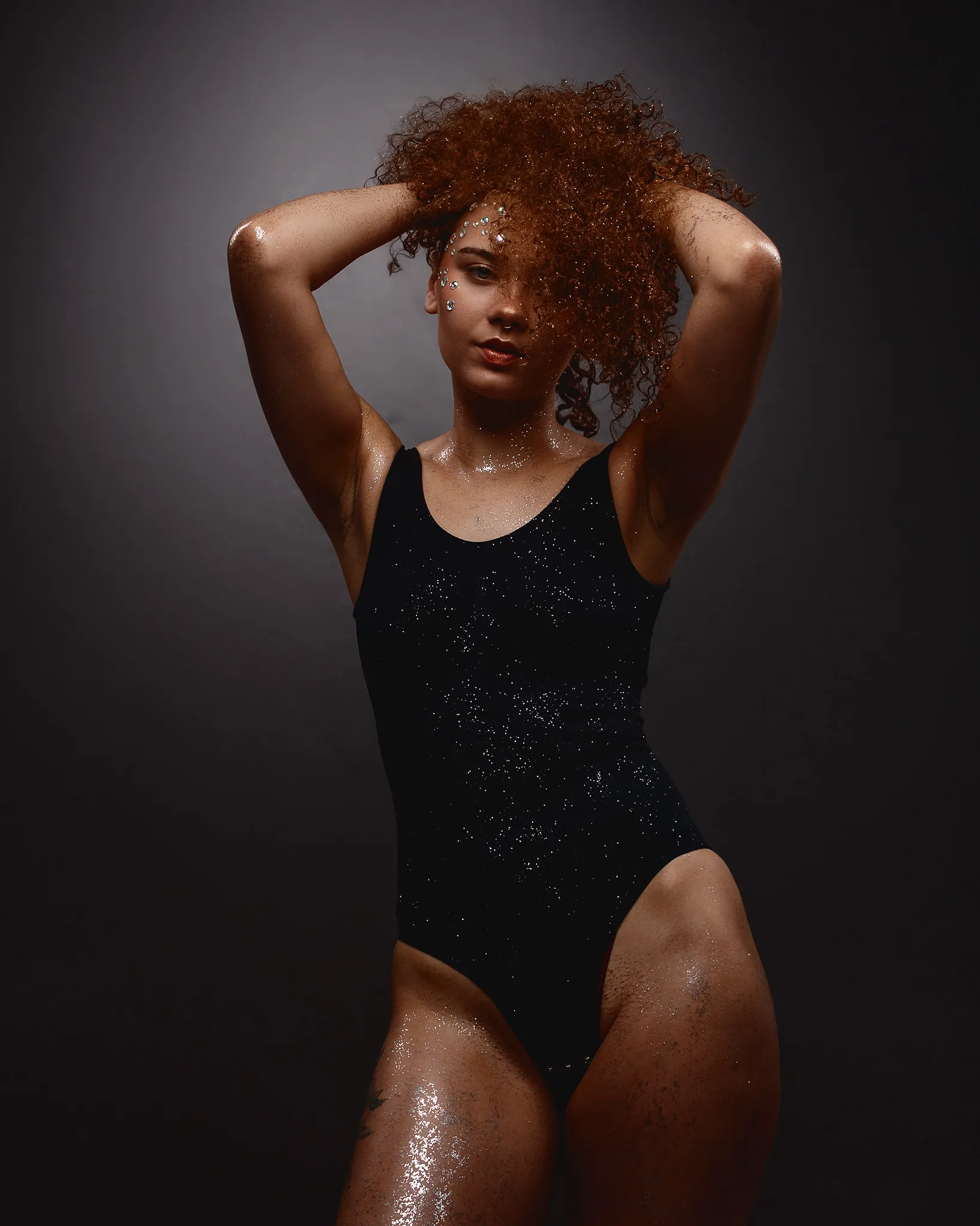 Woman with curly auburn hair wearing black sequined swimsuit