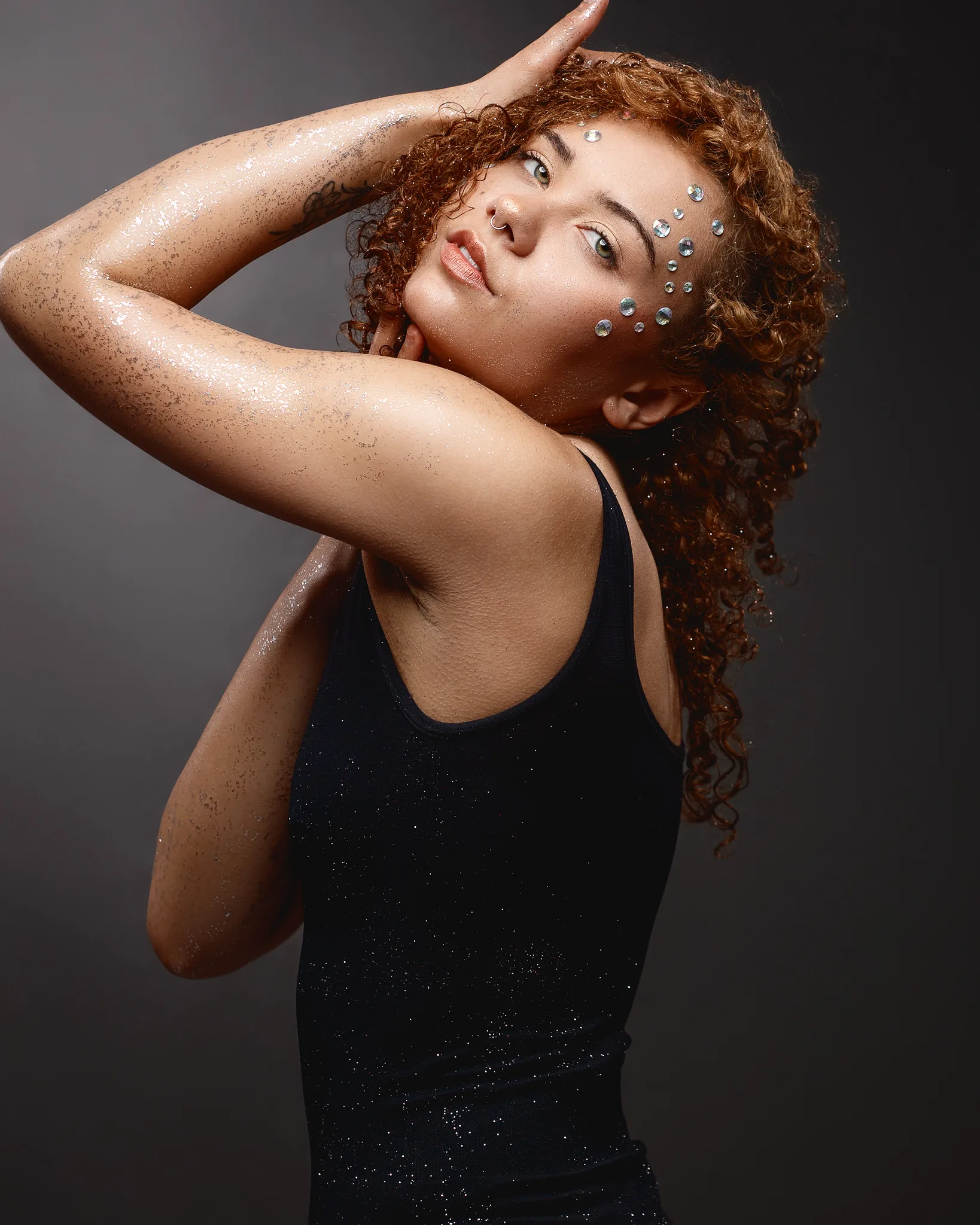 Woman with curly red hair and face gems, wet skin appearance