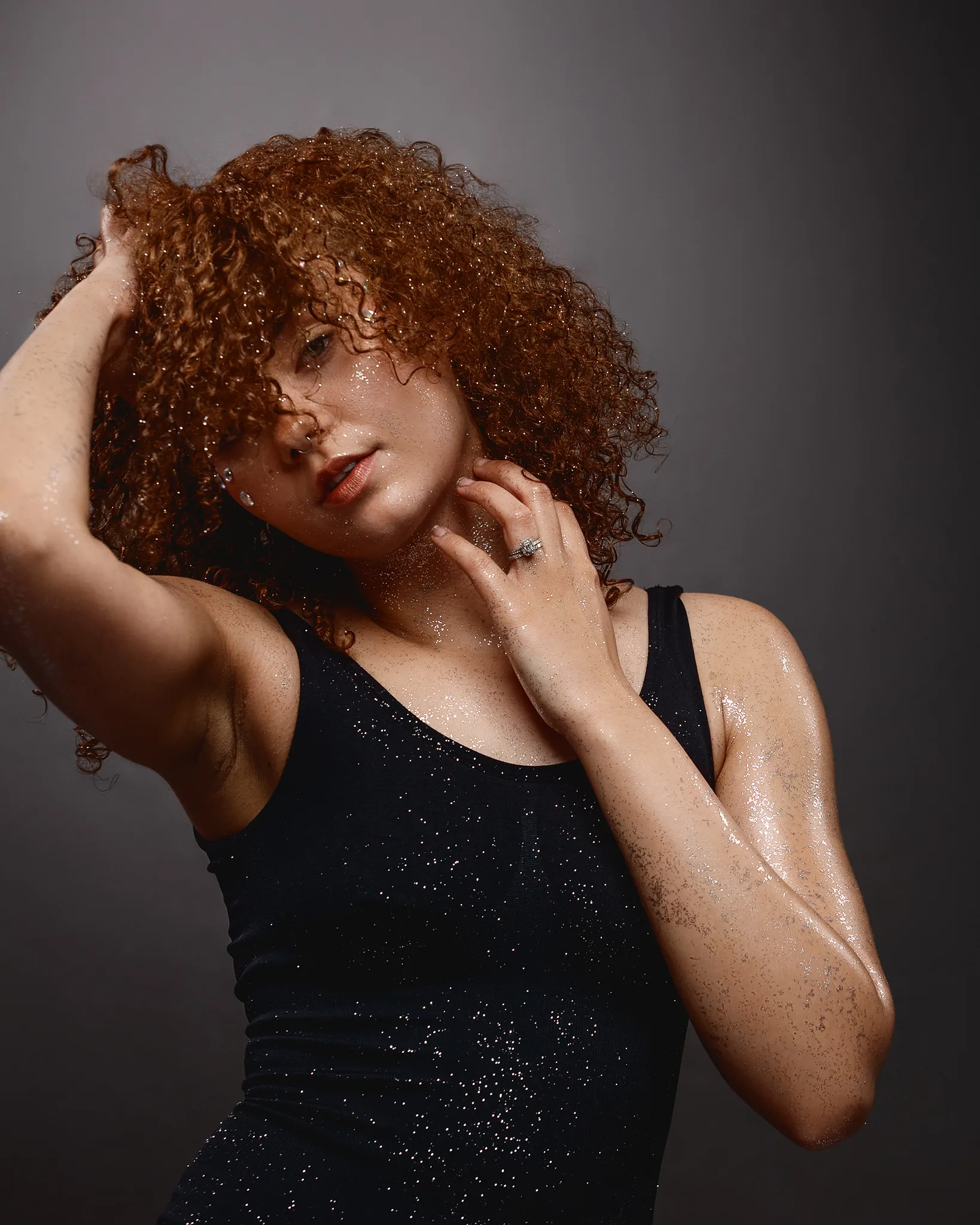 Woman with wet curly auburn hair wearing sparkly black top