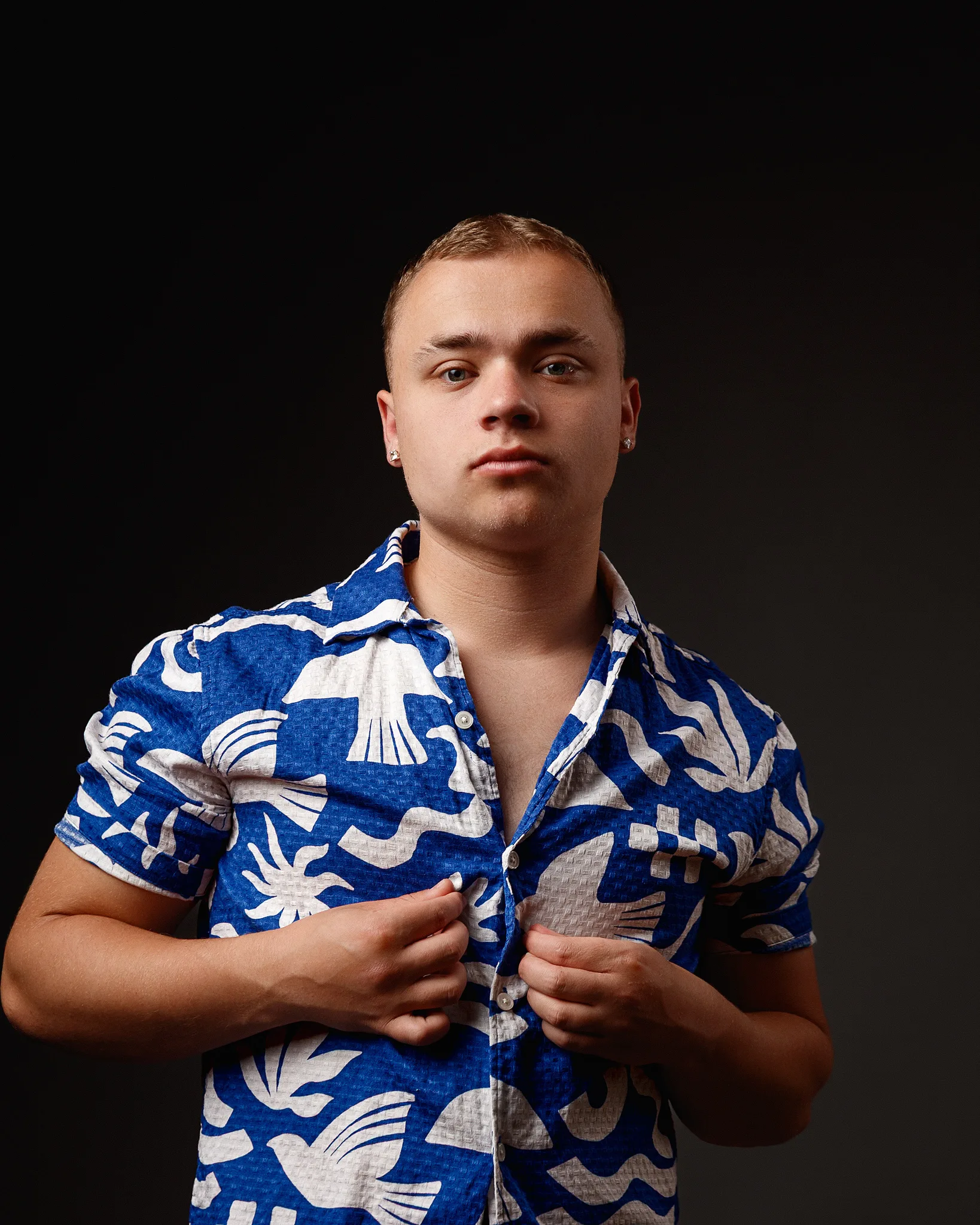 Man wearing blue and white patterned shirt against black background